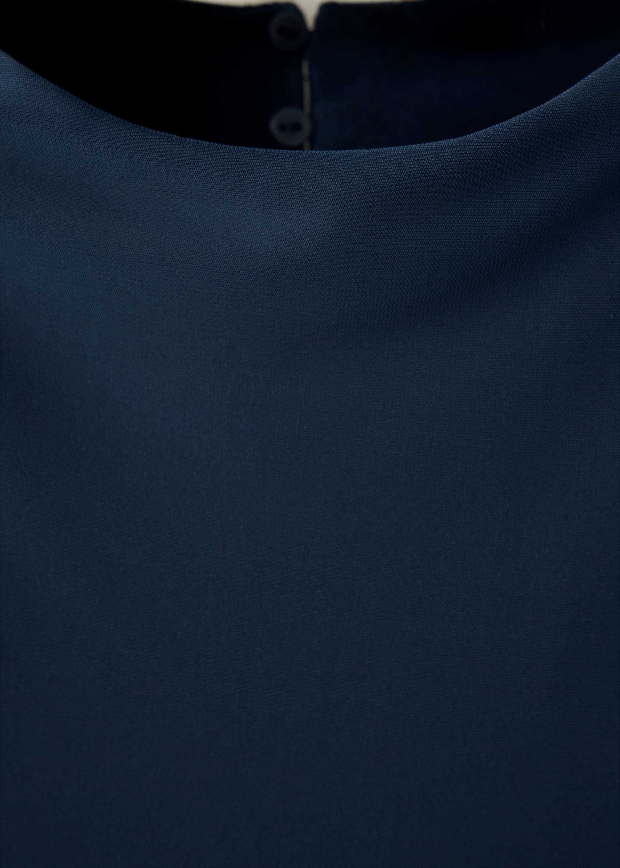 Primer plano del escote y el tejido del vestido azul oscuro.
