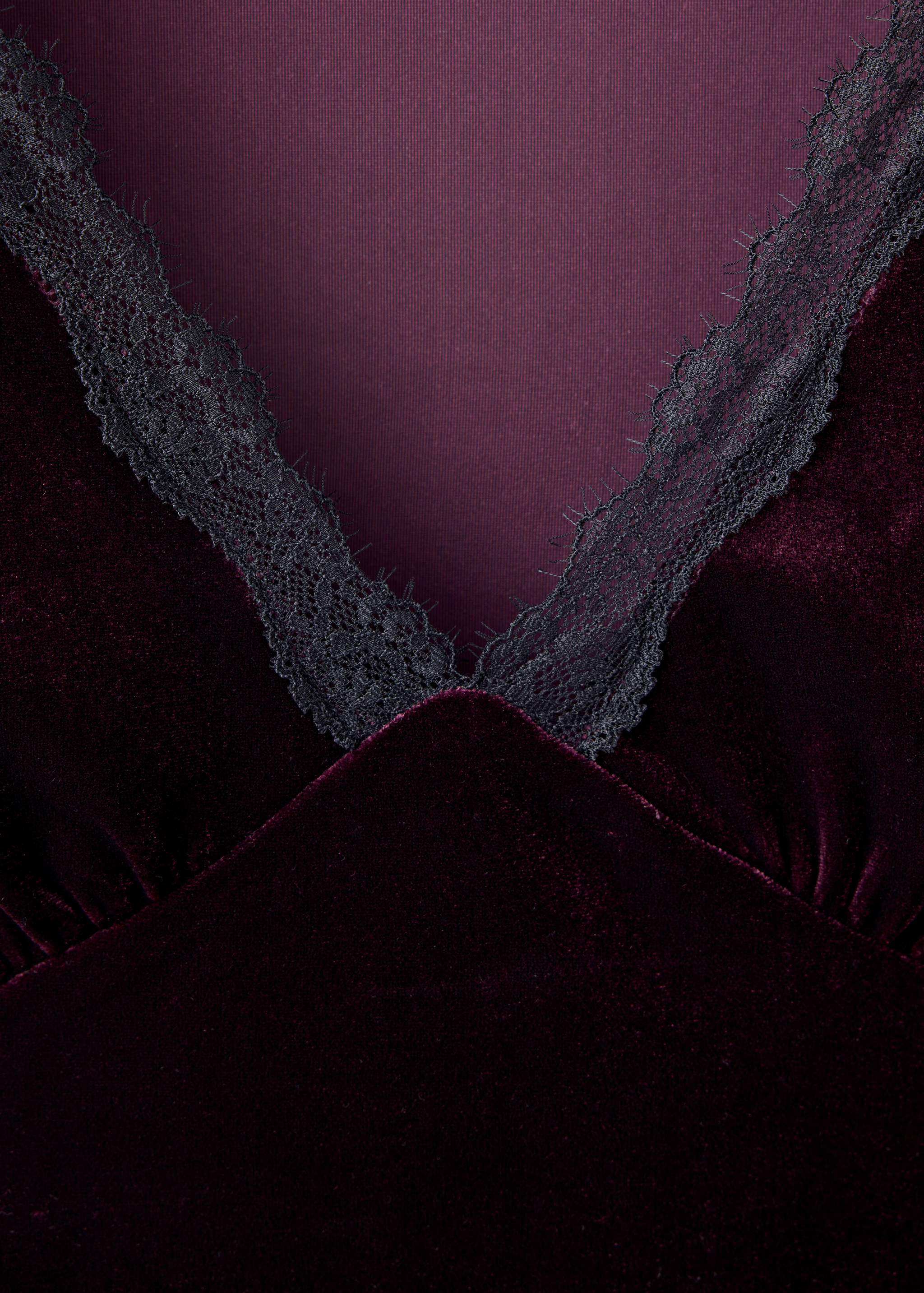 Close-up of a burgundy velvet top with black lace V-neck trim.
