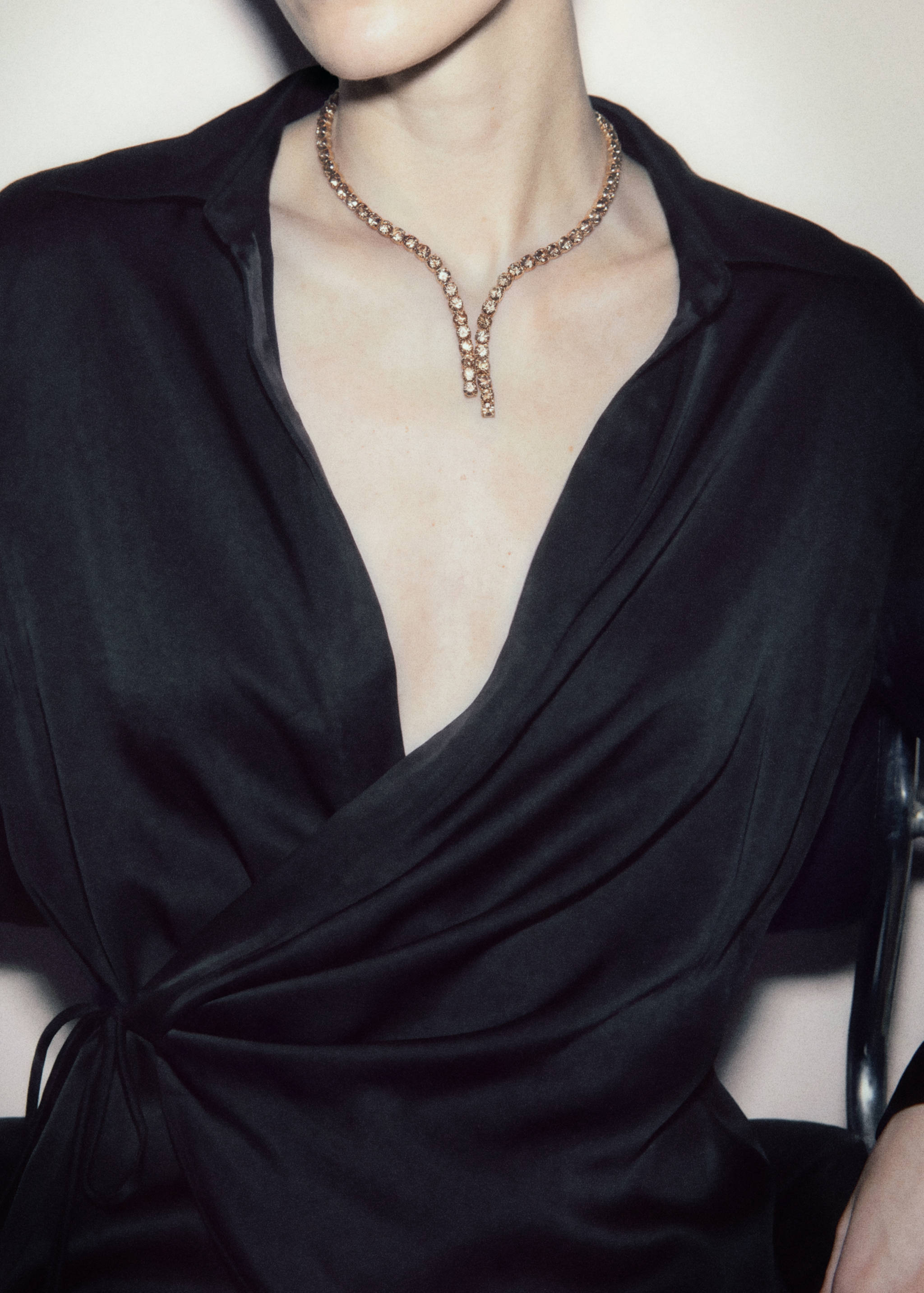 Sparkly rhinestone collar necklace worn with a black satin wrap blouse.