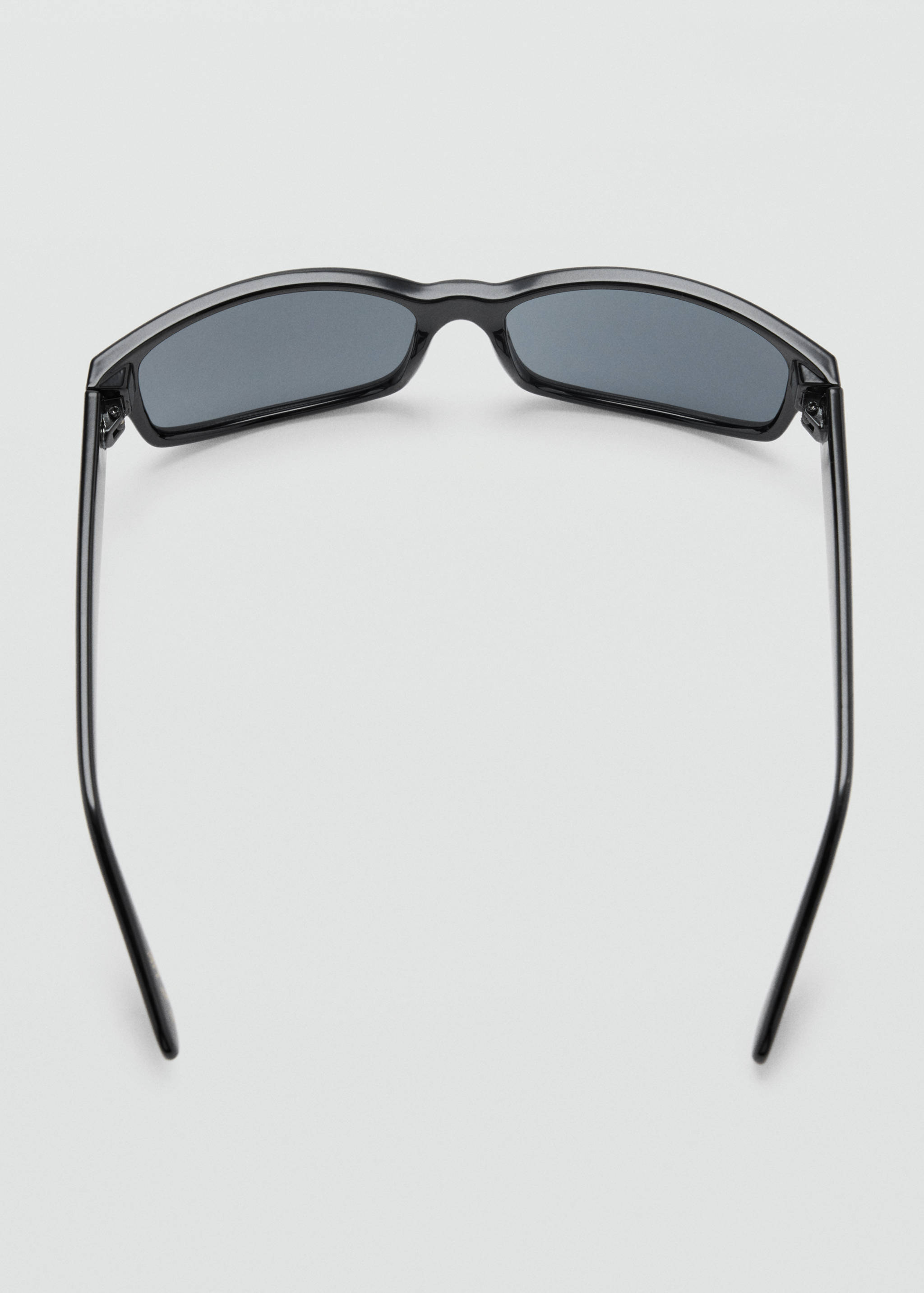 Vista de detalle trasera de las gafas de sol negras con lentes y montura oscuras.