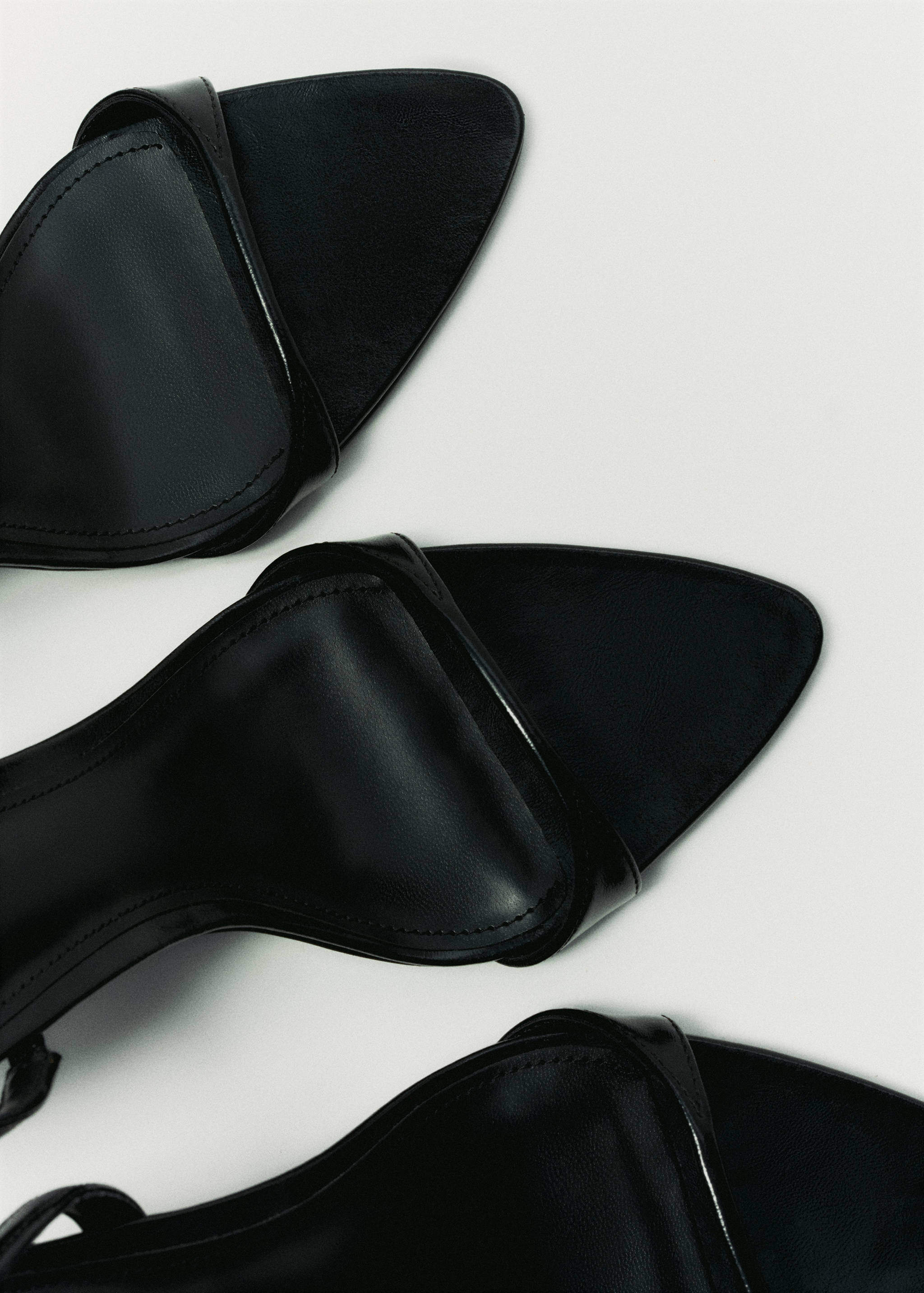 Close-up of black sandals with a pointed toe and thin straps.