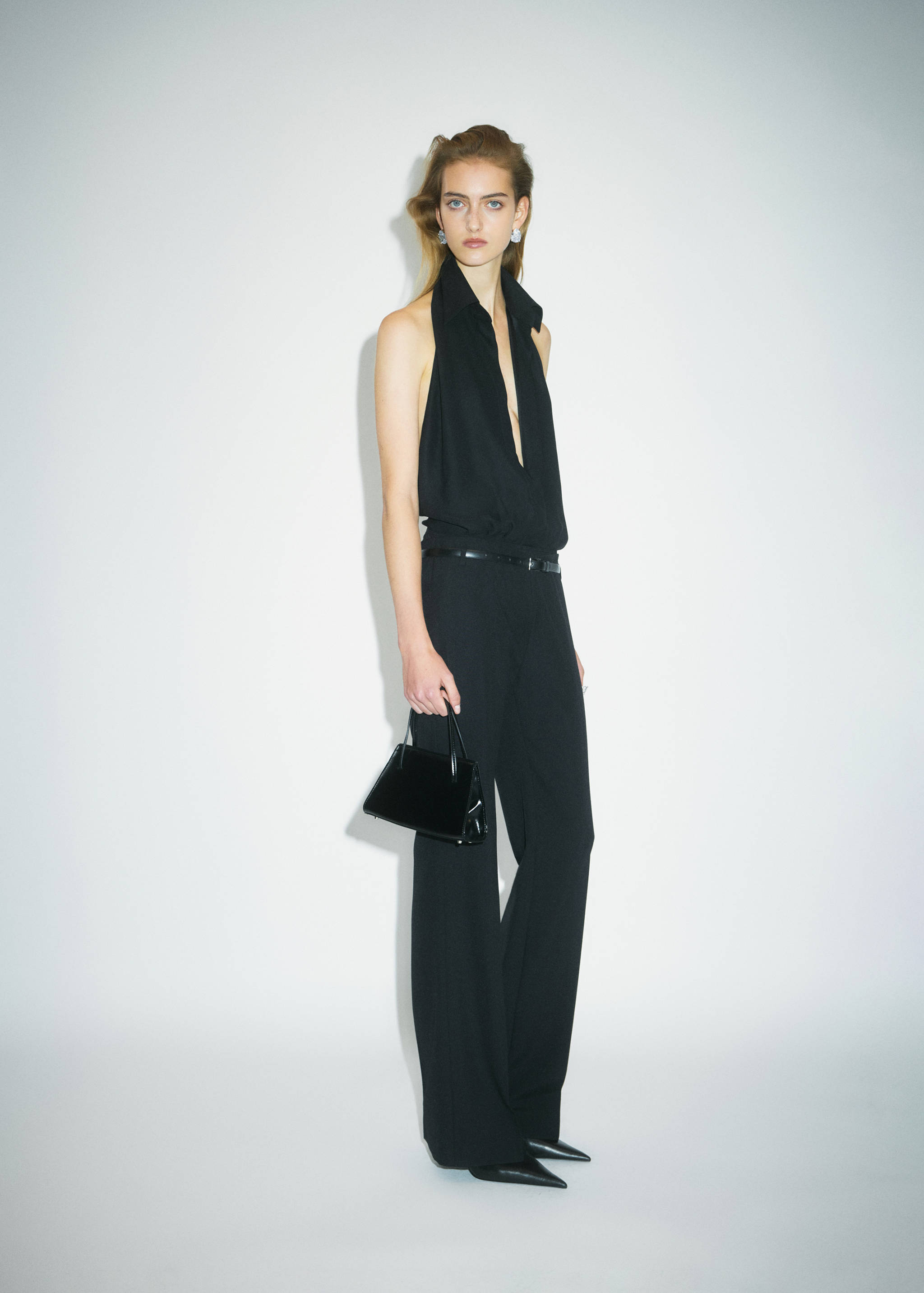 Black straight-leg trousers, worn with a matching halter top and handbag.