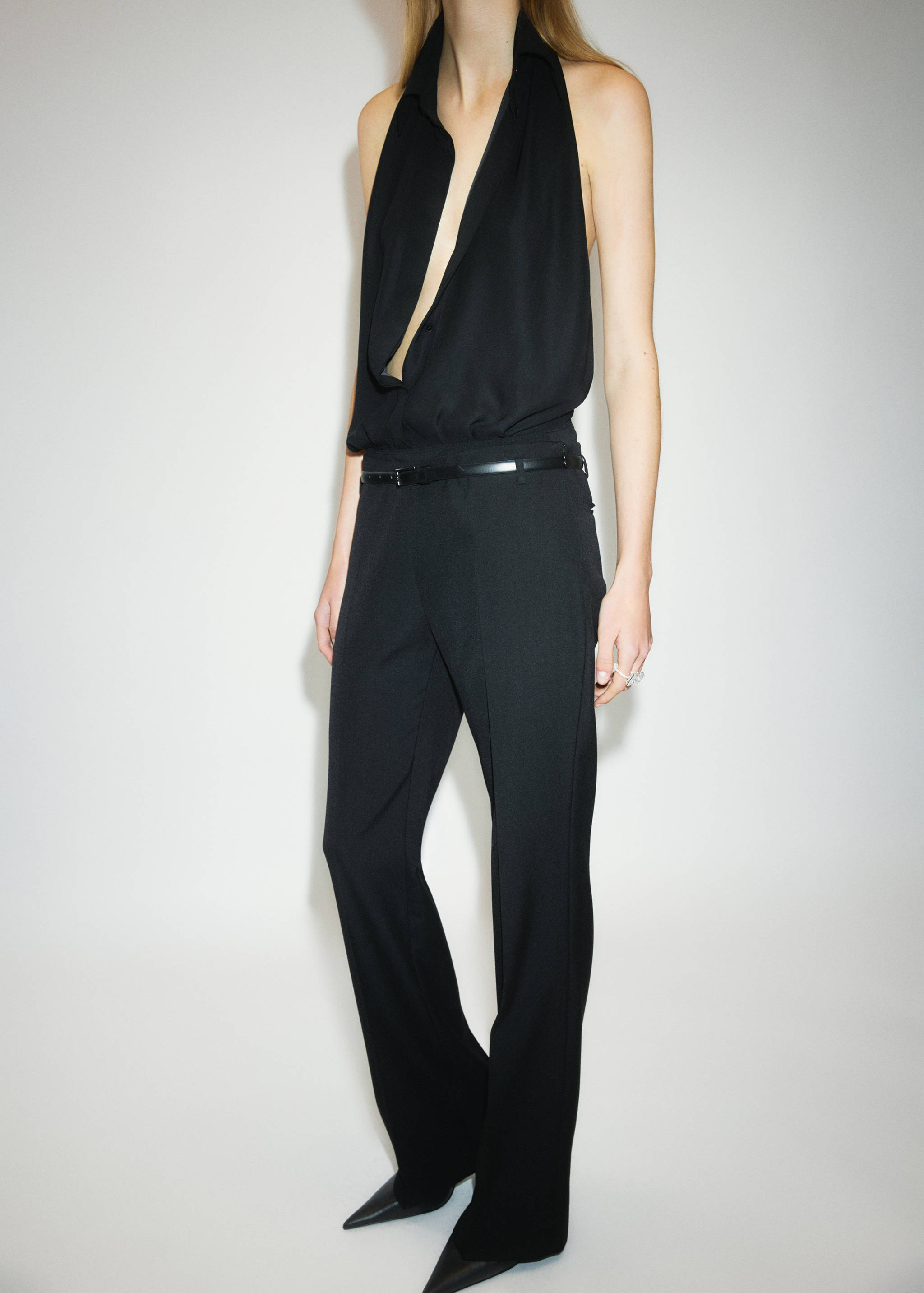 Black trousers styled with a black halter-neck top and a thin belt.