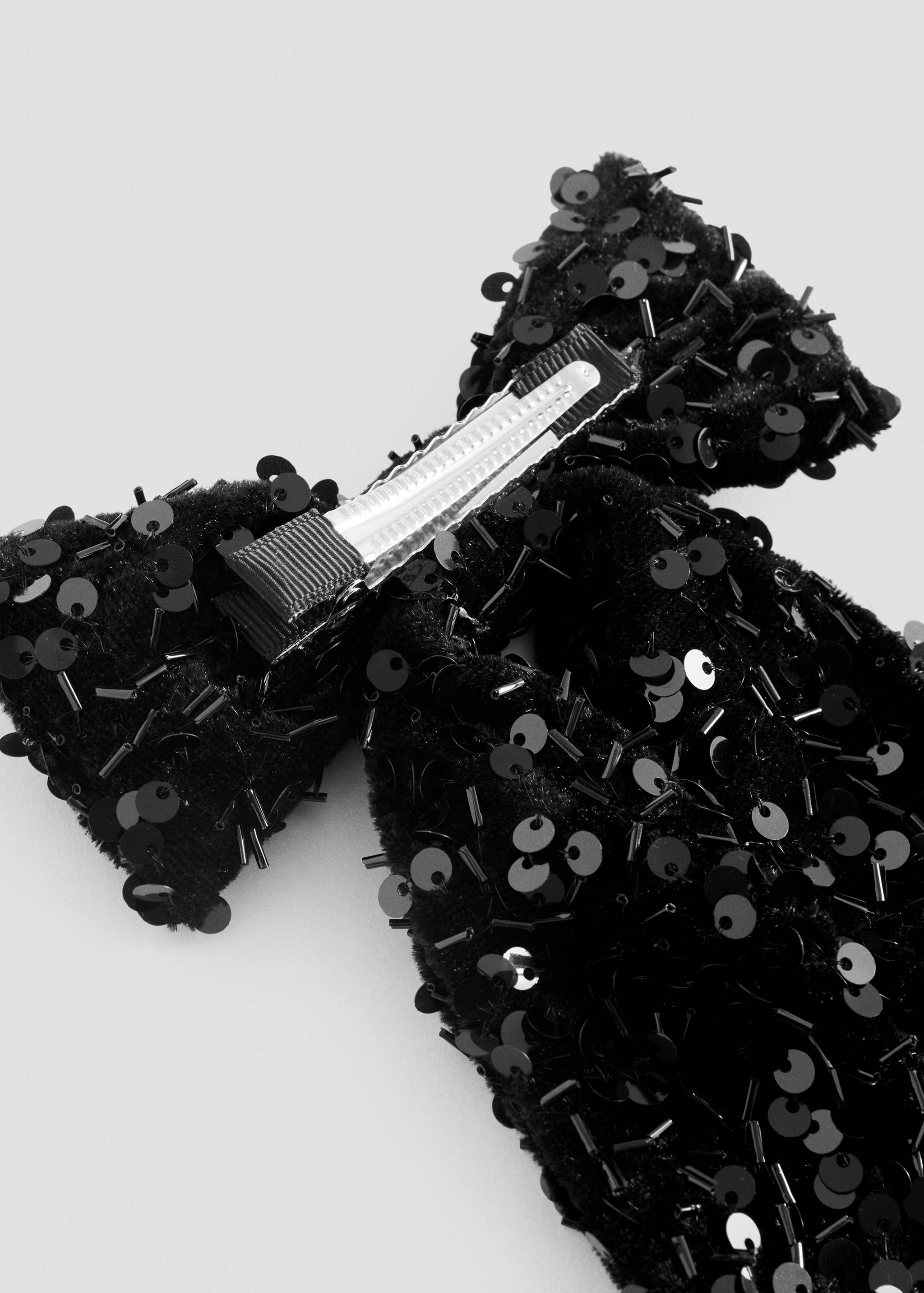 Close-up of the reverse of a black sequinned bow hair clip.