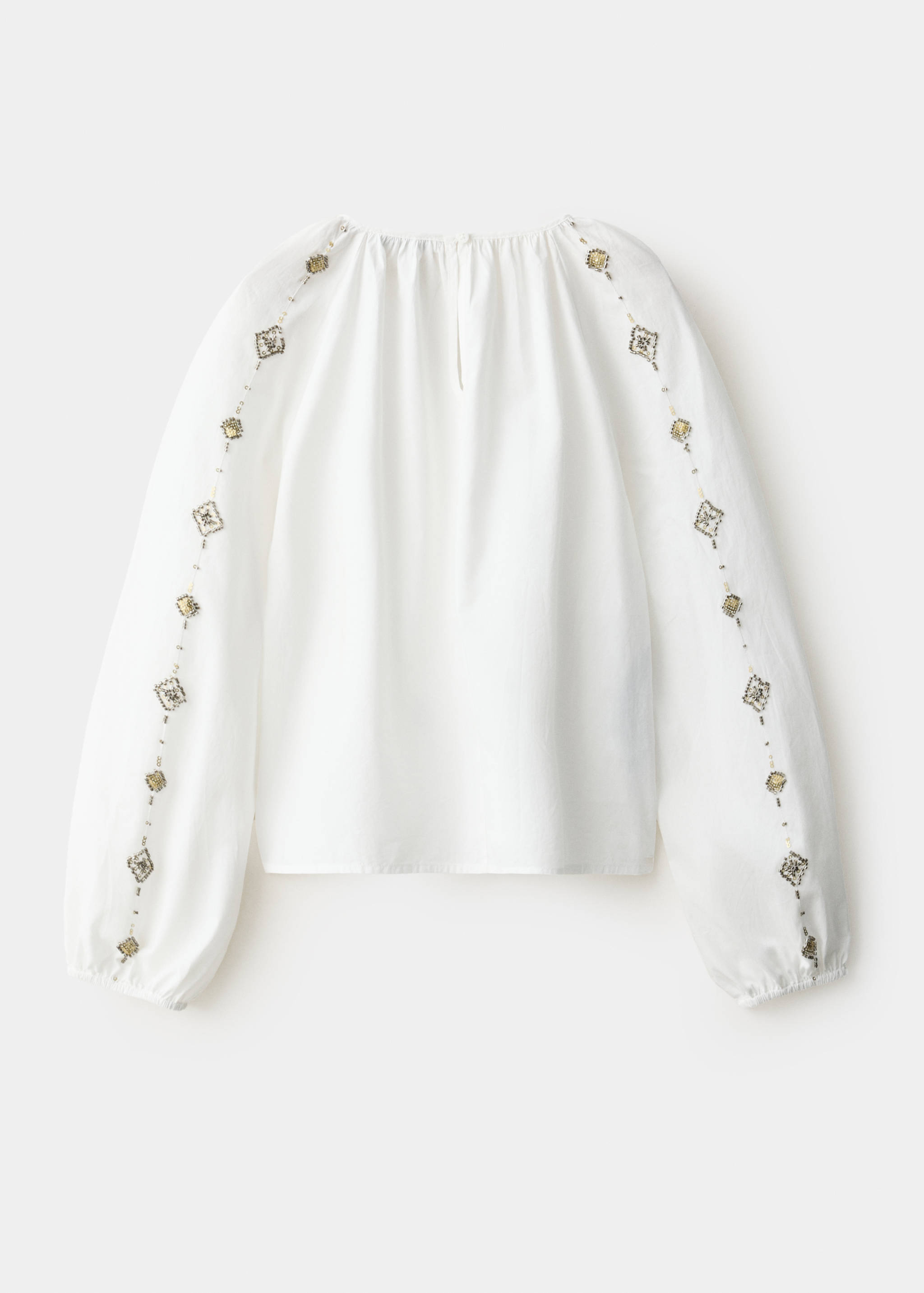 White blouse with beaded long sleeves, shown from the back.