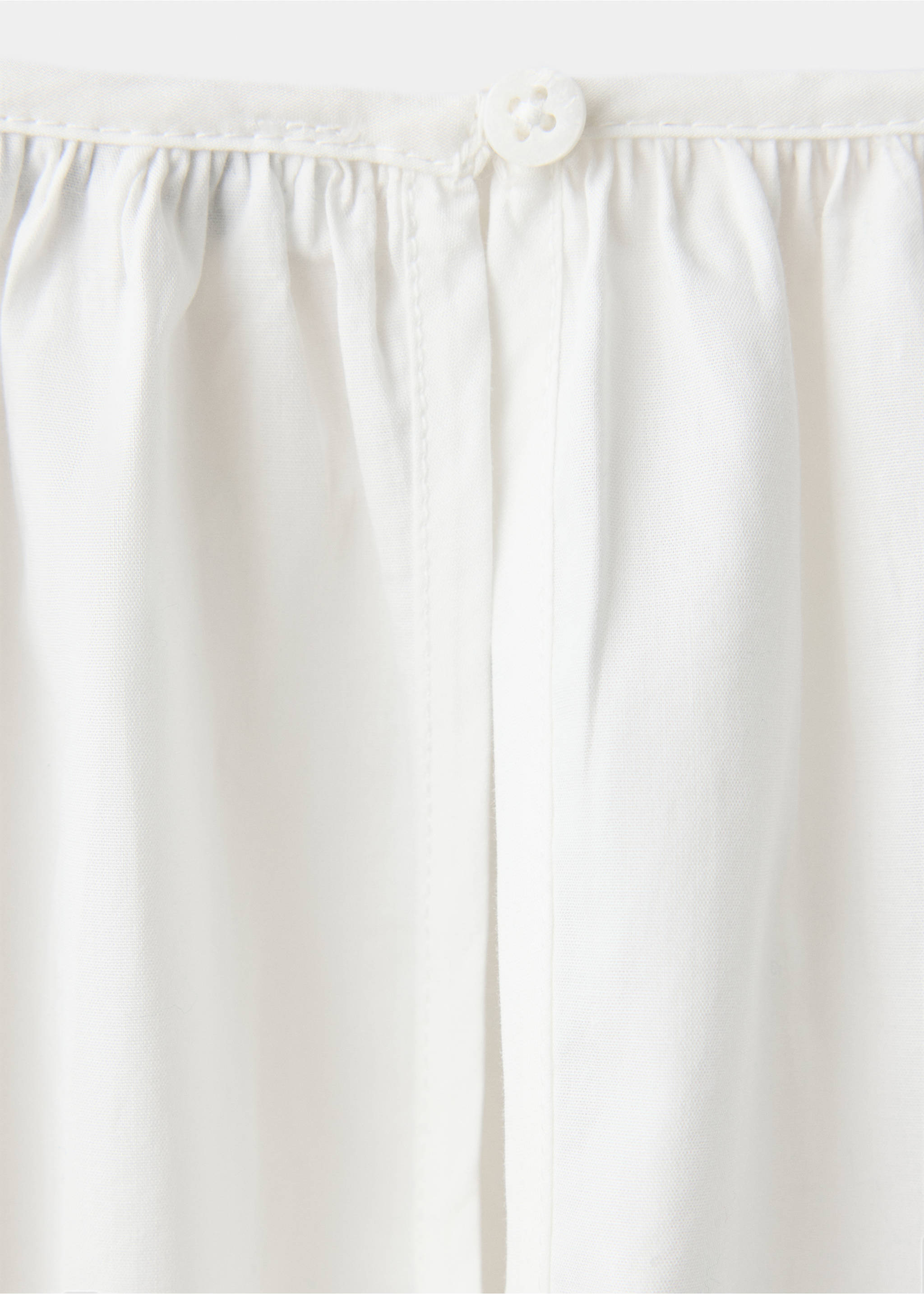 Close-up of white children's blouse fabric with gathered neckline and button., White. Ref: 37039221-00.