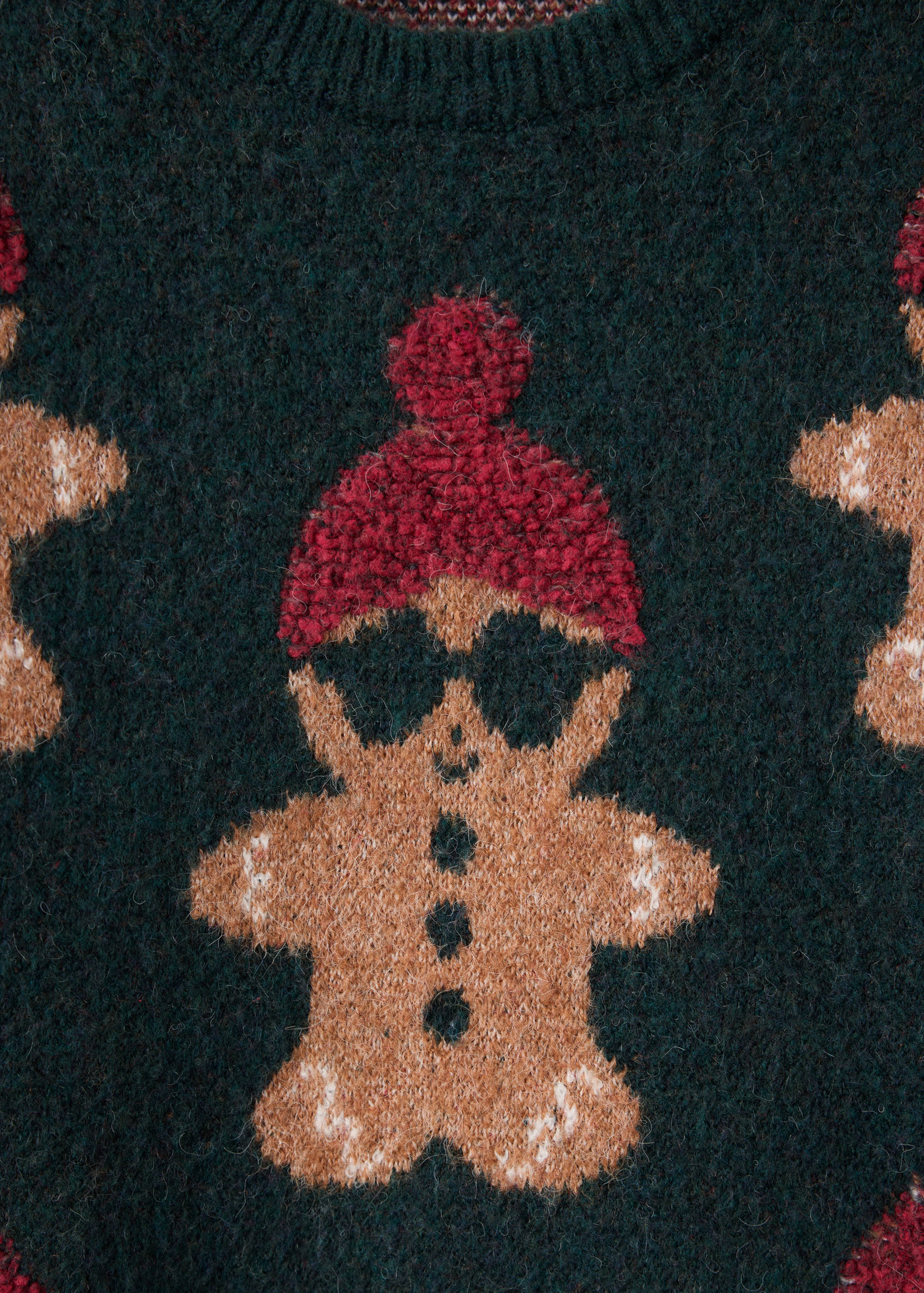 Close-up of a dark green sweater featuring a gingerbread man with a red beanie.