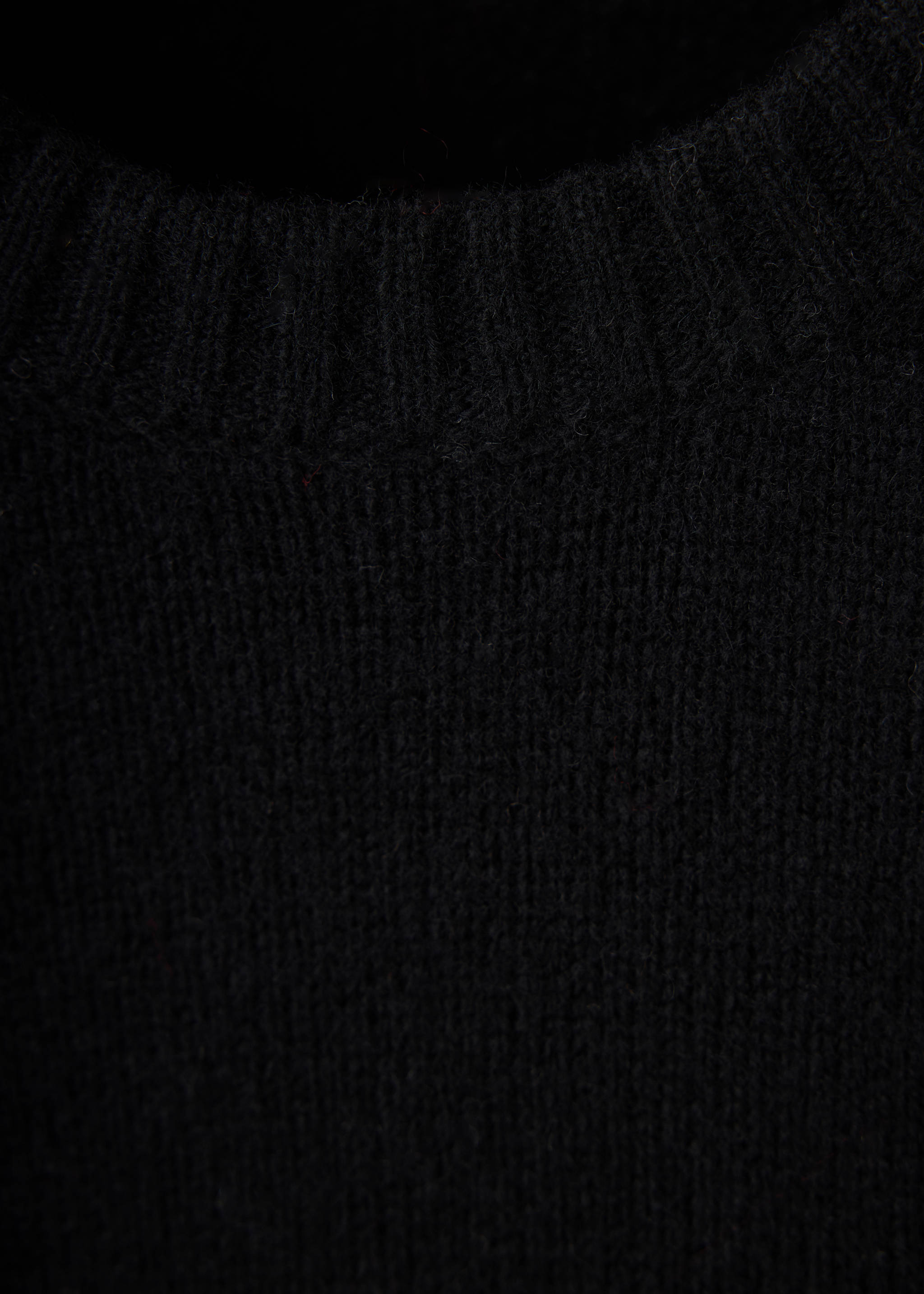 Close-up of a black knitted crew neck jersey.