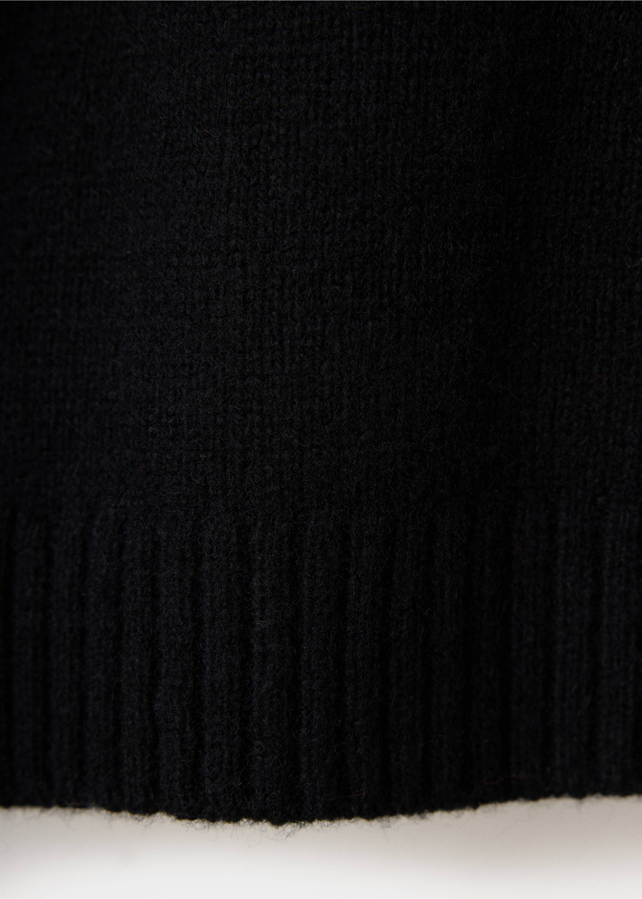 Close-up of the black knit fabric and ribbed hem of a sweater., Black. Ref: 37039227-00.