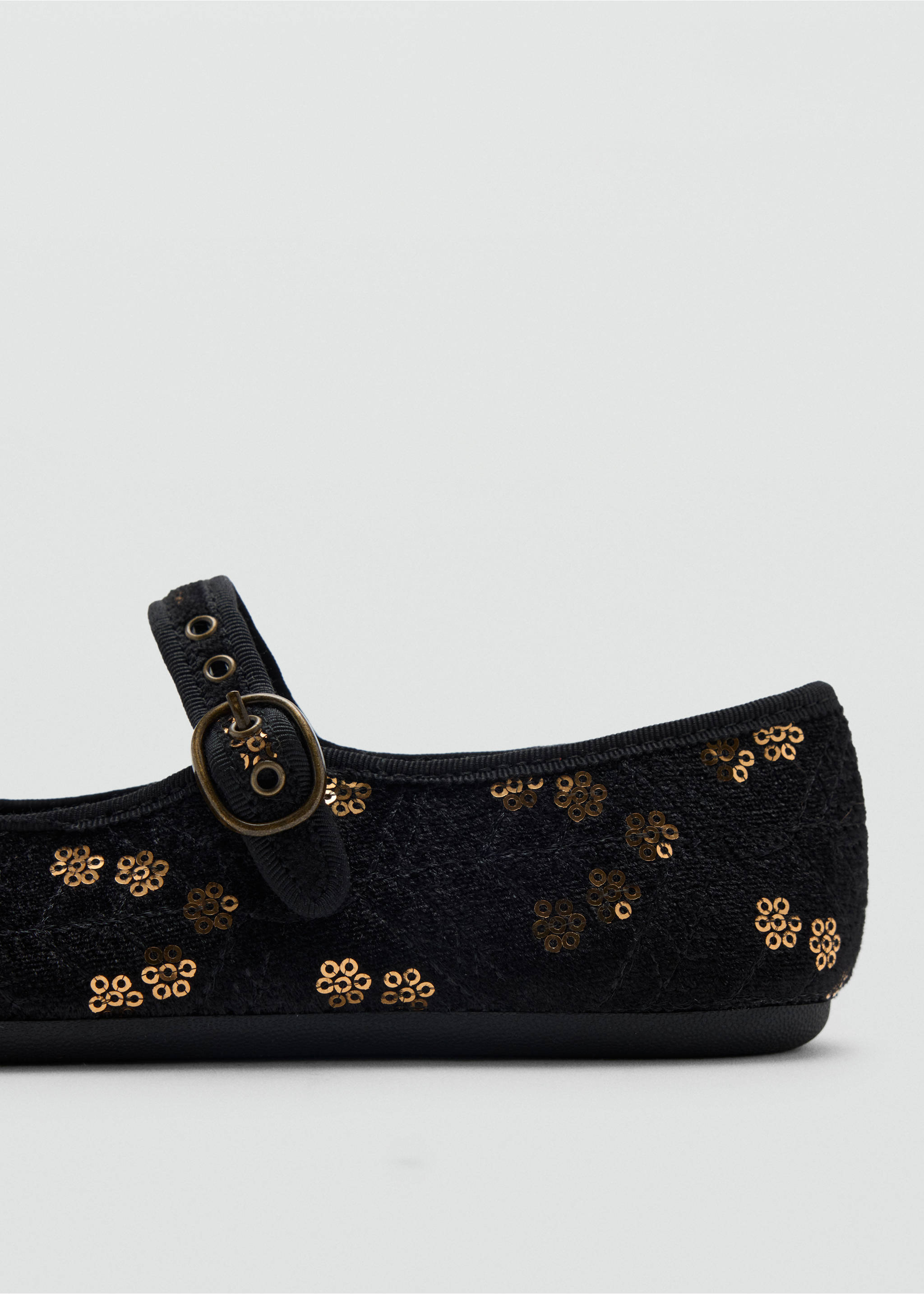 Close-up of a child's black shoe with bronze sequin flowers and a buckled strap., Black. Ref: 37039229-00.