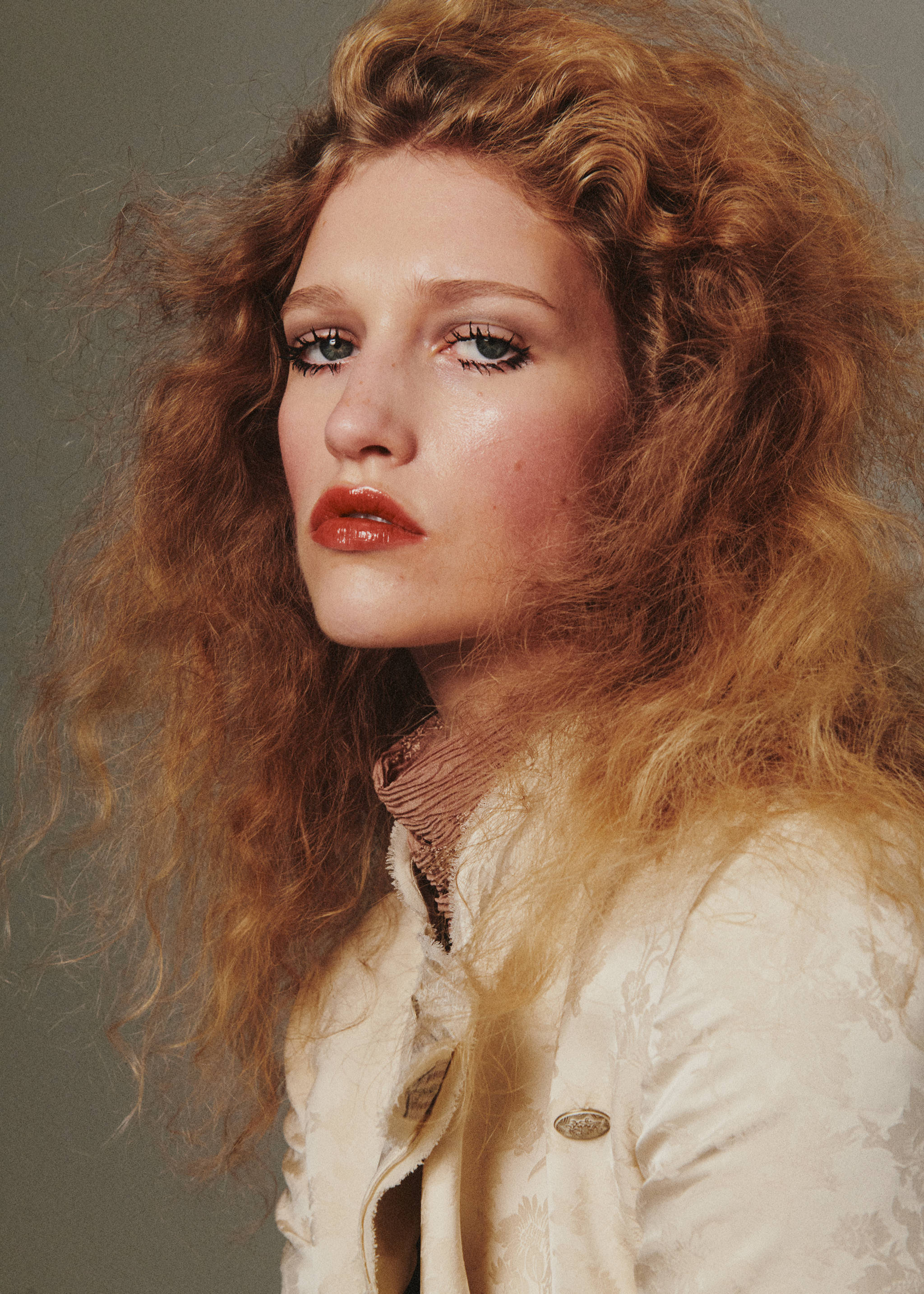 Cream patterned jacket with a high collar and metallic buttons, worn by a model.