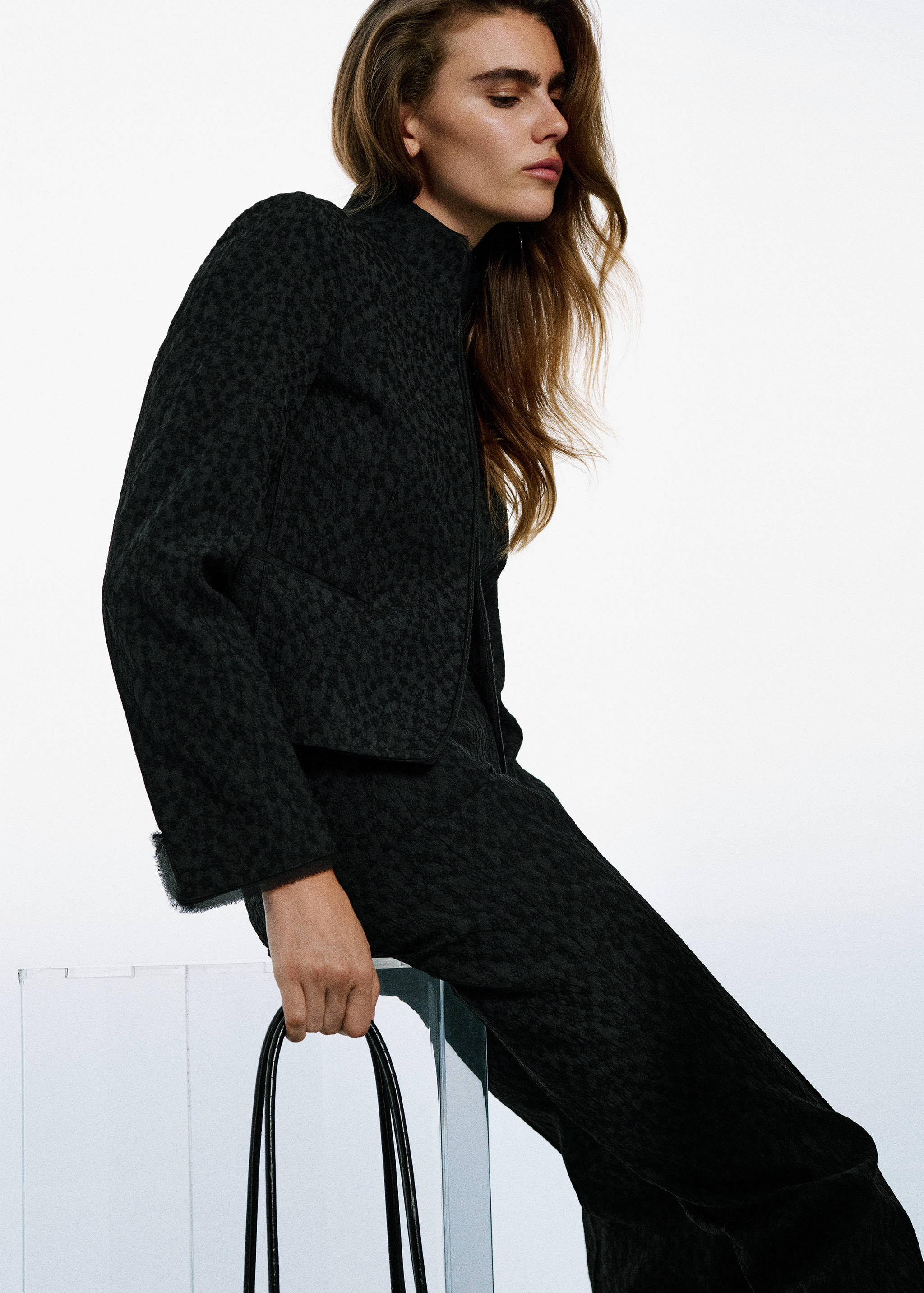 Black textured trousers worn with a matching cropped jacket.