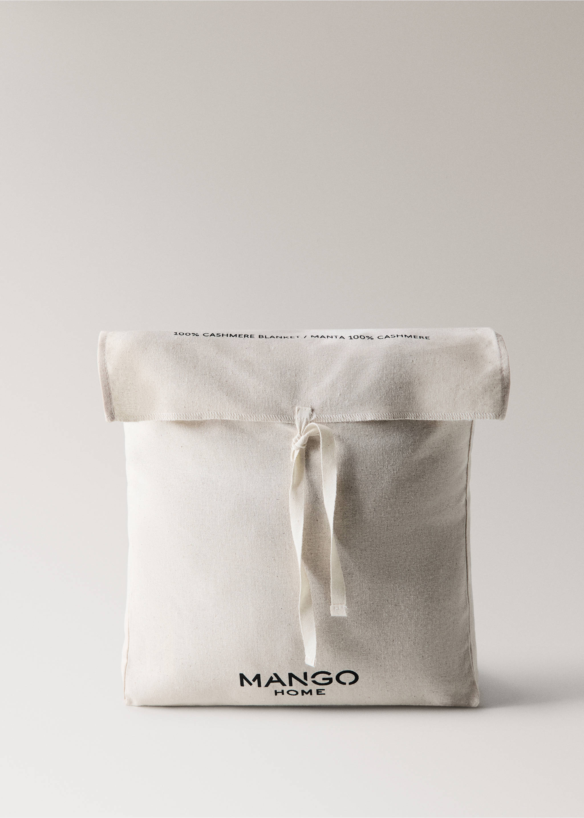 Off-white cotton storage pouch with drawstring and Mango Home branding, containing a cashmere blanket., Beige. Ref: 37042554-00.