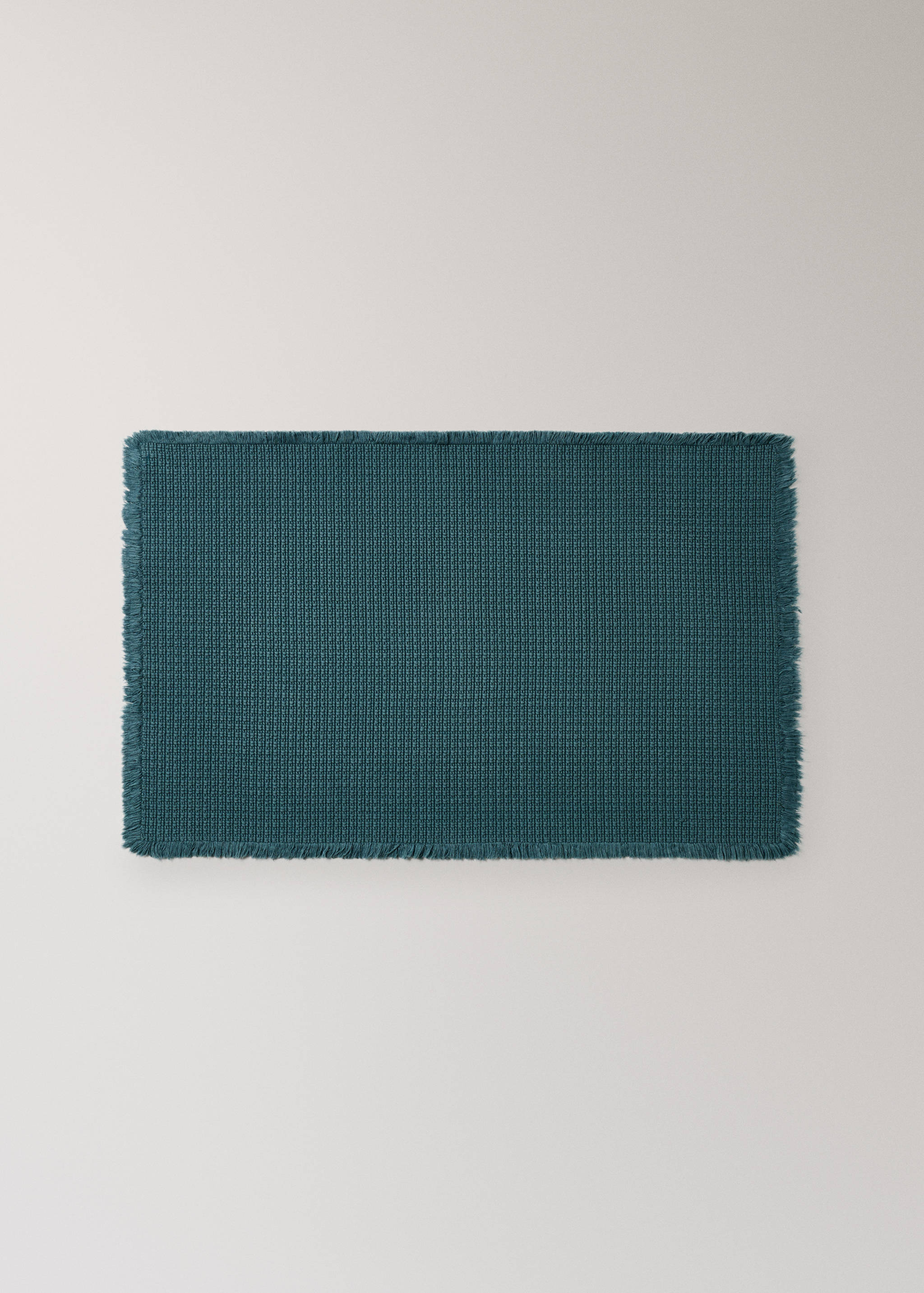 Teal bathroom mat with a textured waffle-weave pattern and fringed edges.