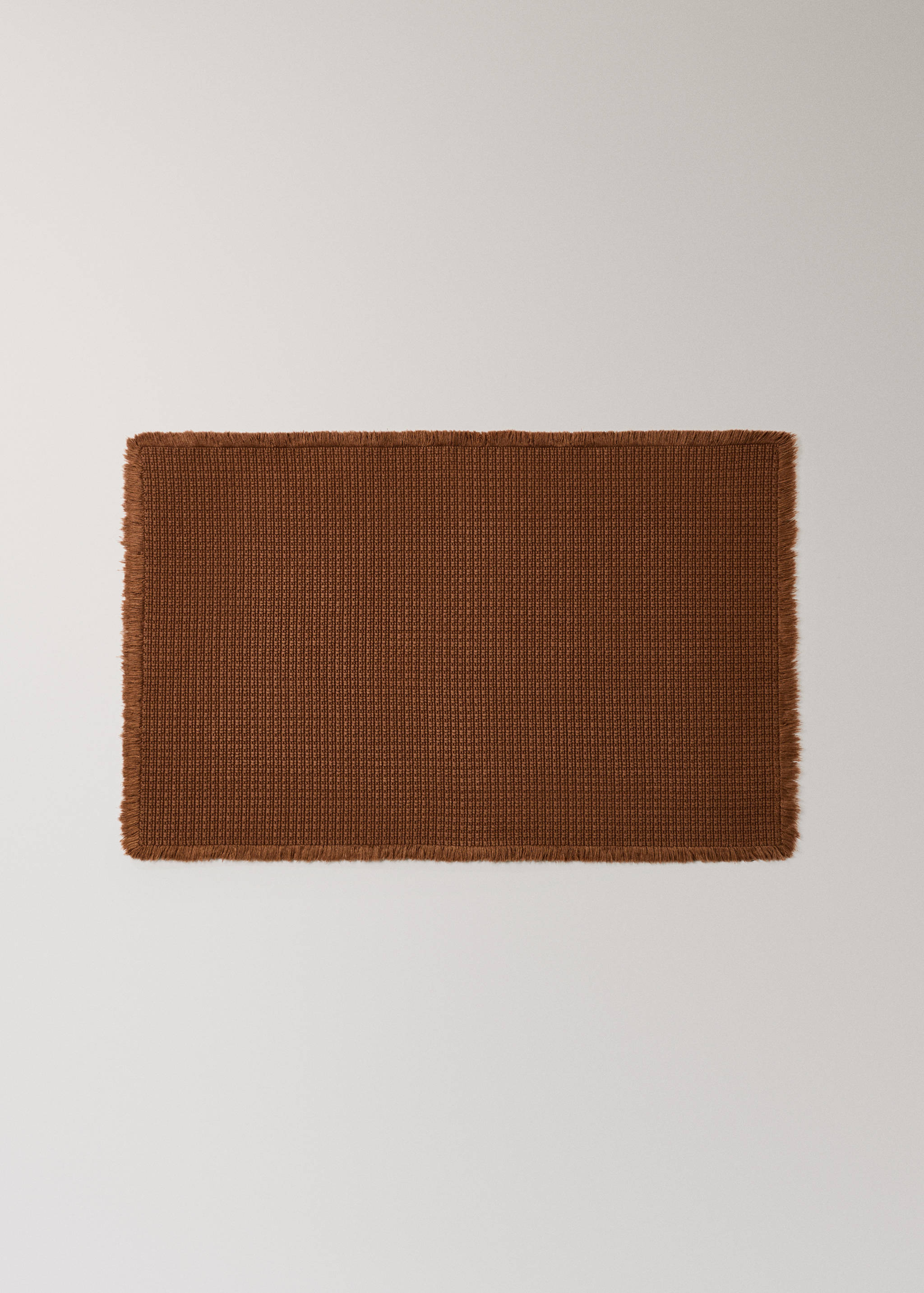 Brown waffle-weave bathroom mat with fringed edges.