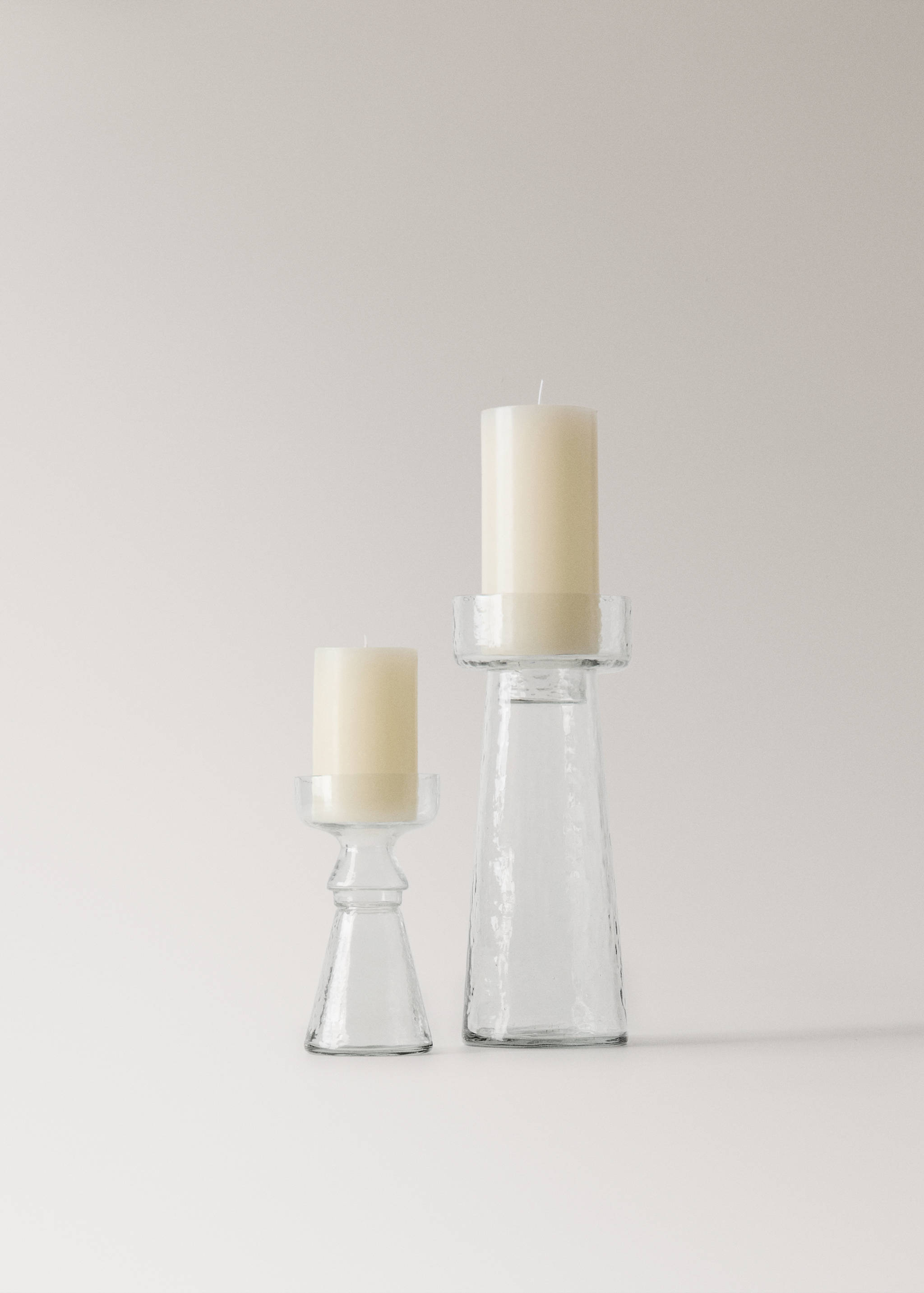 Two clear glass candle holders with cream pillar candles.