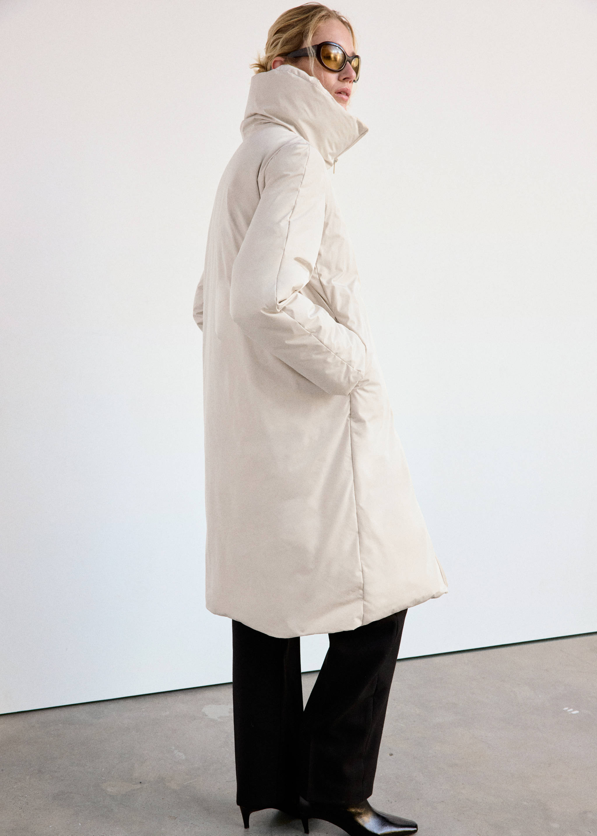 Cream-coloured long anorak with high collar.
