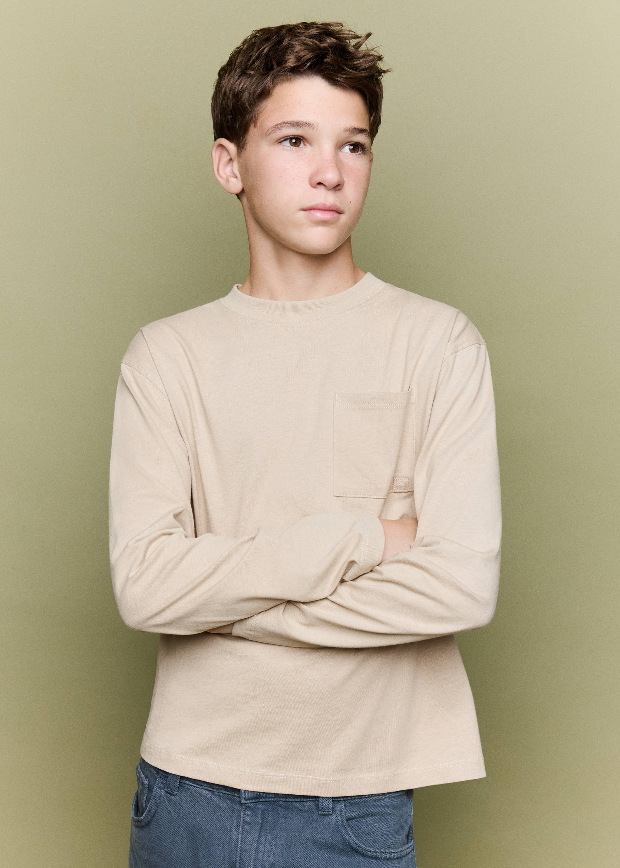 Beige long-sleeved t-shirt with a crew neck and chest pocket.
