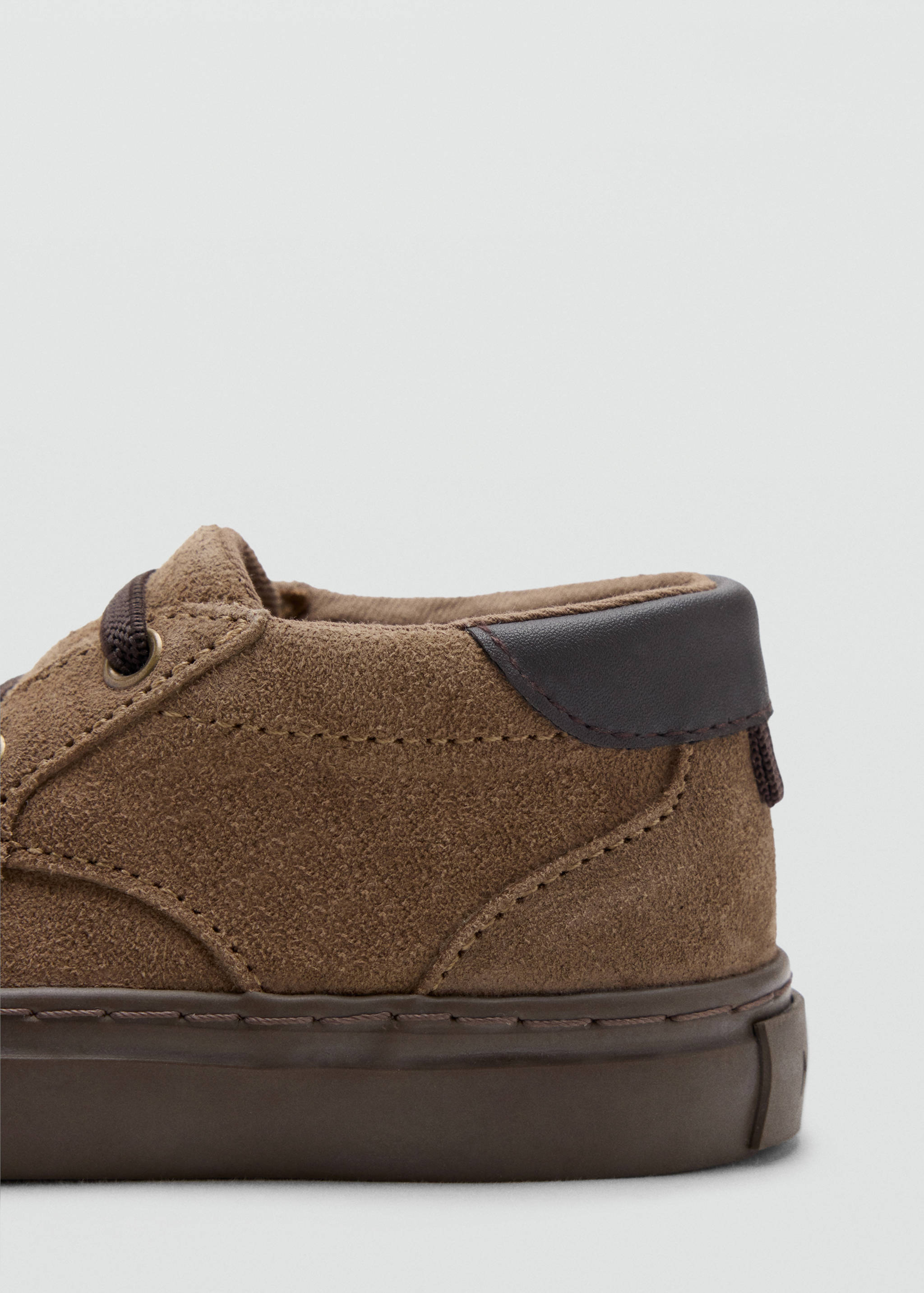 Close-up of a brown suede children's shoe with a dark brown heel tab and laces.