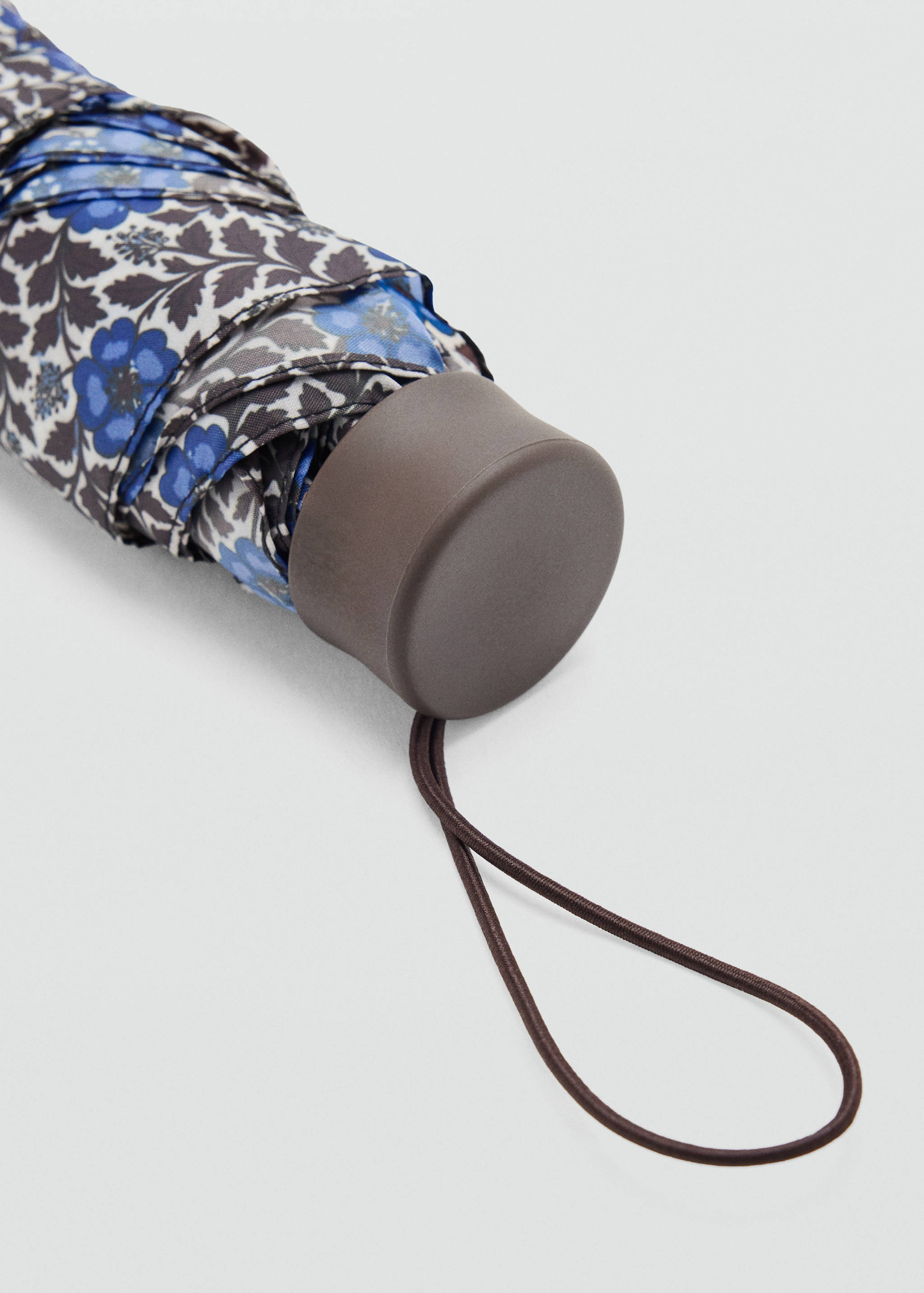 Close-up of a folded blue floral umbrella with a brown handle.