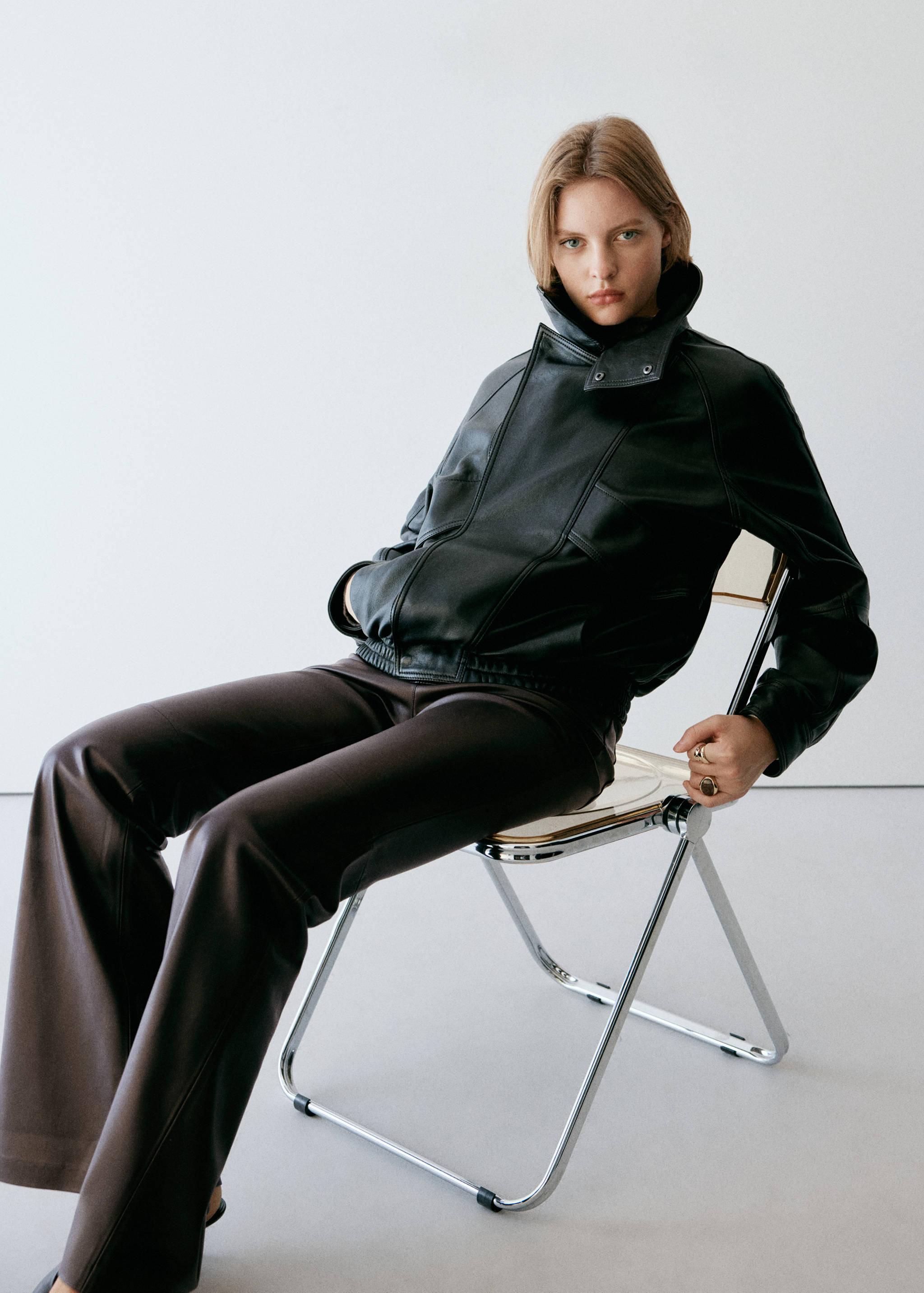 Dark brown trousers worn with a black leather bomber jacket.