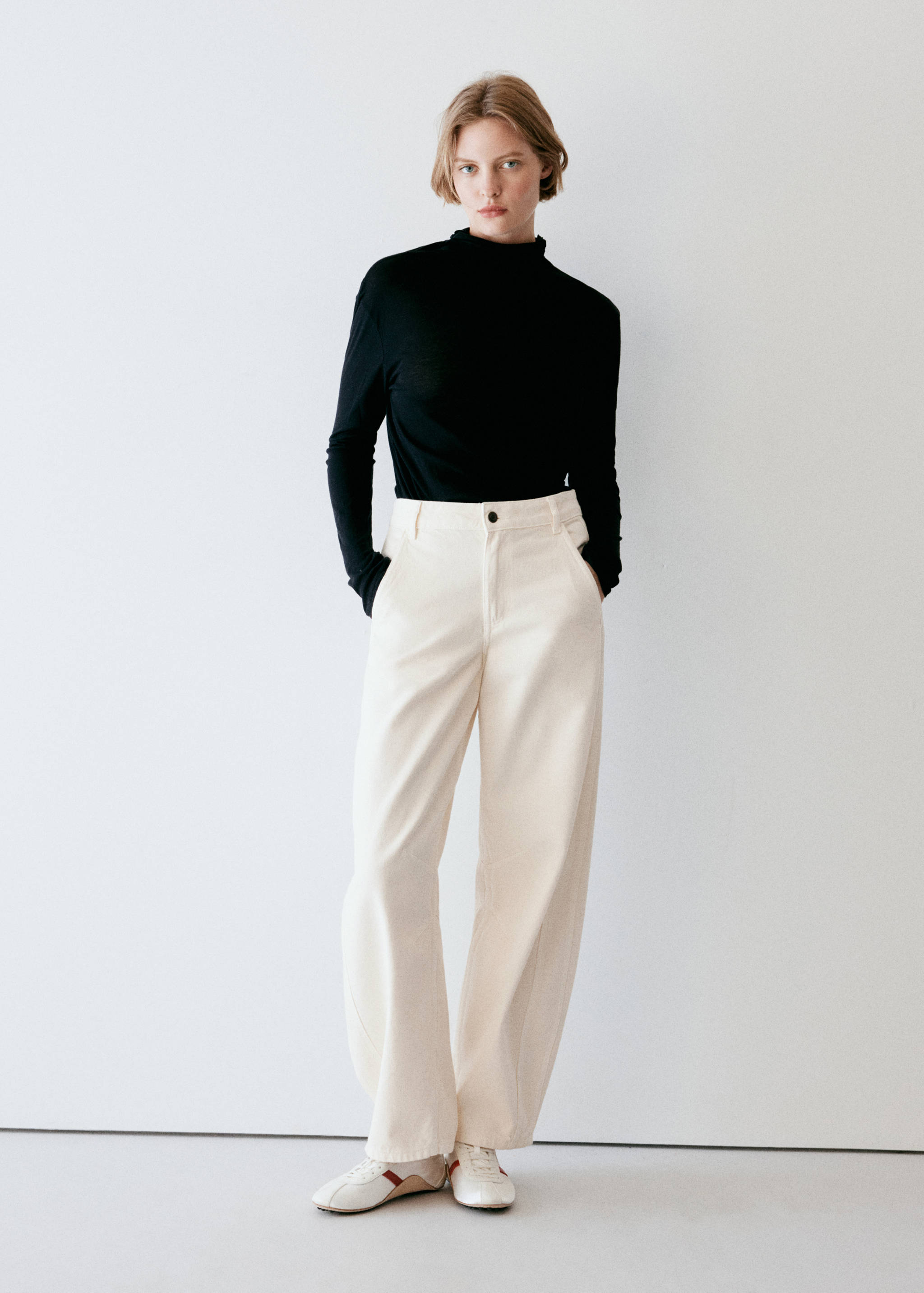 Cream white wide-leg trousers paired with a black long-sleeved top.