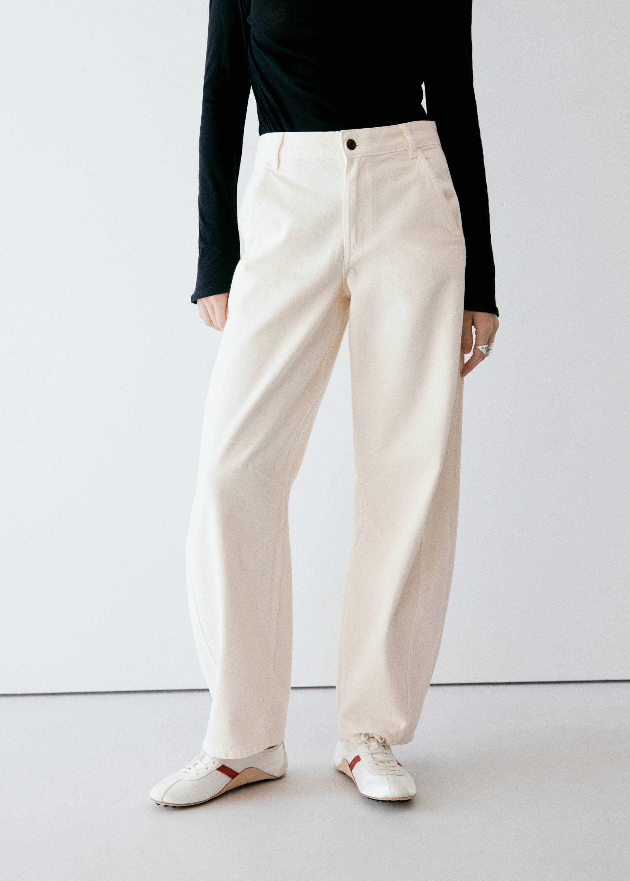 Cream high-waisted wide-leg trousers with curved knee seams.