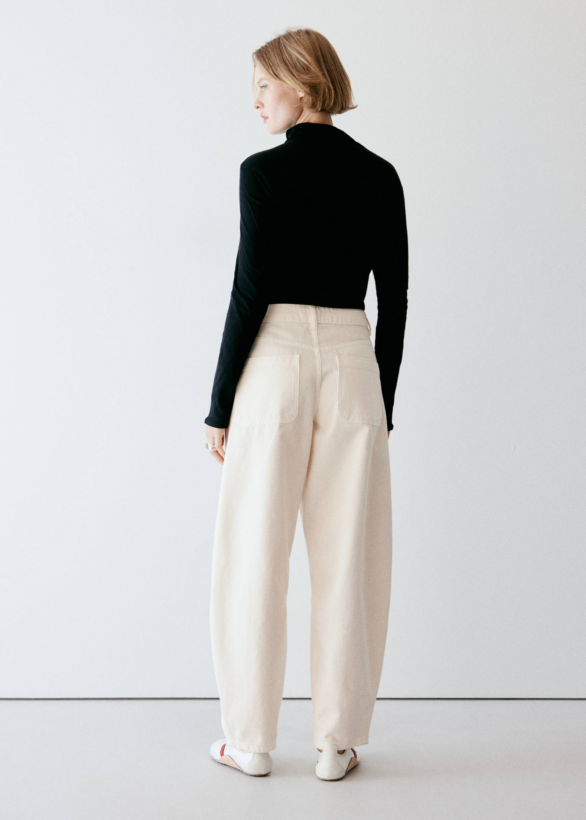 Cream trousers in a relaxed curved-leg fit, back view.
