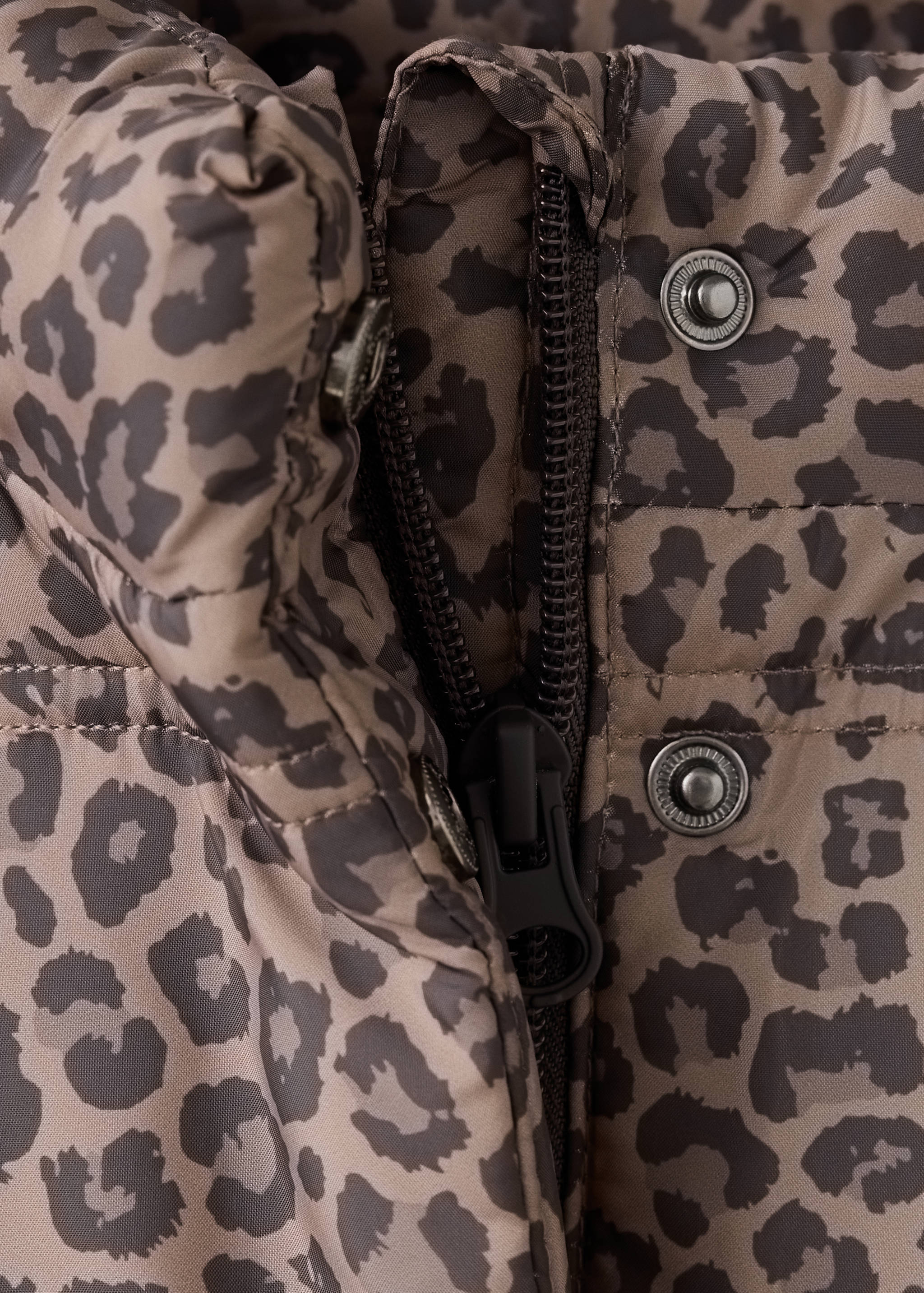 Close-up of a brown leopard-print anorak showing the zipper and snap button details.