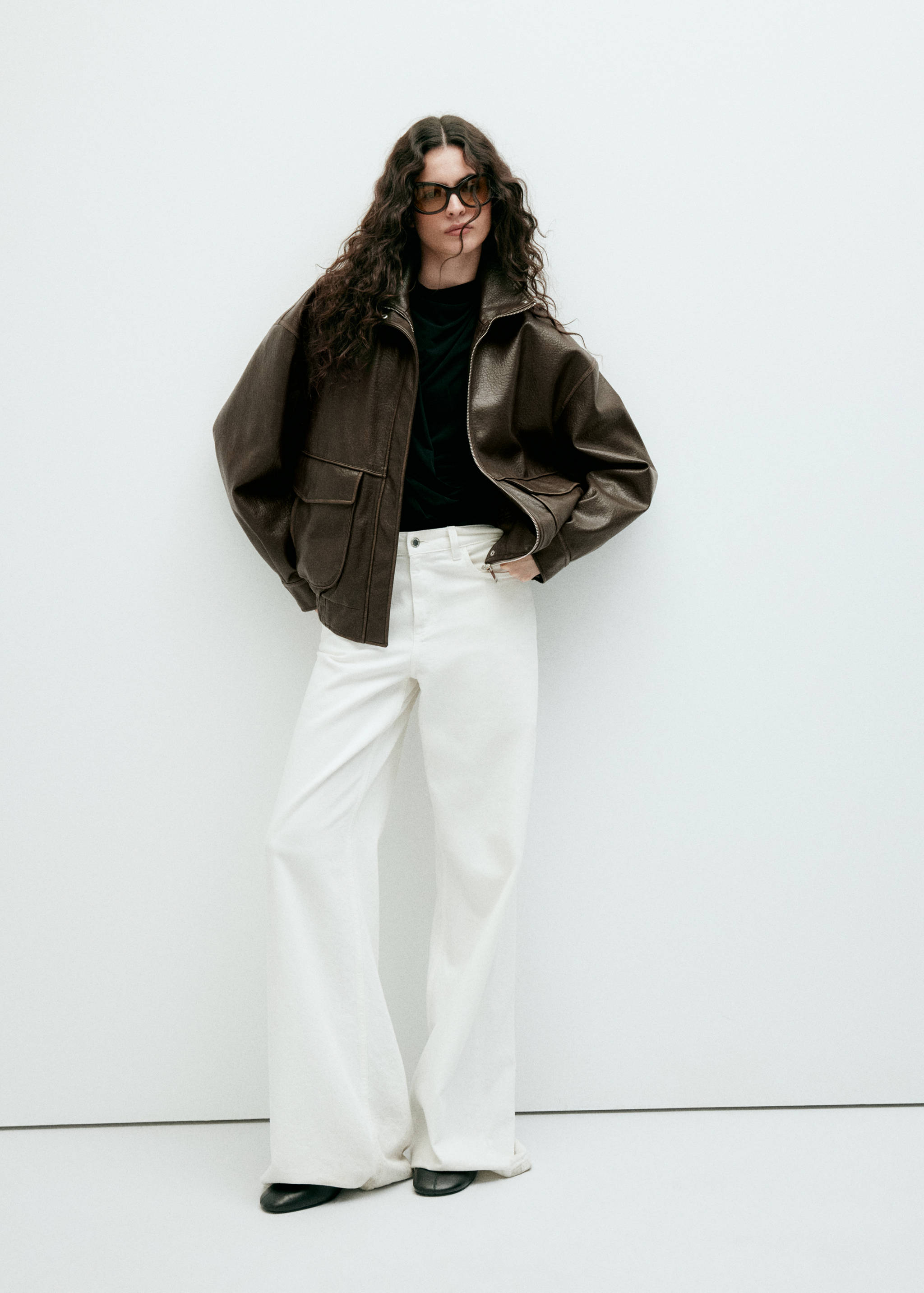 Oversized dark brown leather jacket with a high collar and front pockets.