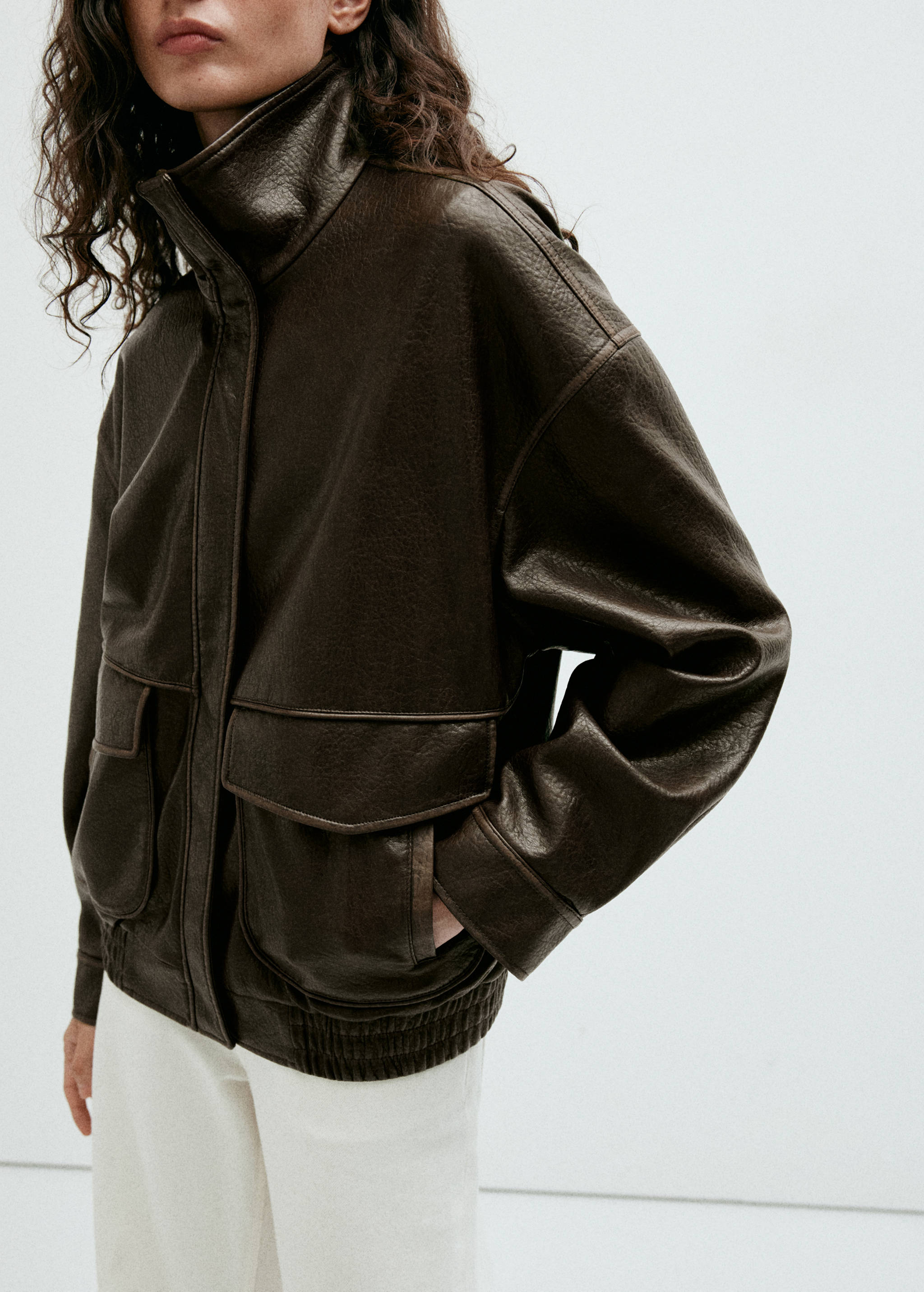 Dark brown textured faux-leather jacket with high neck and flap pockets.