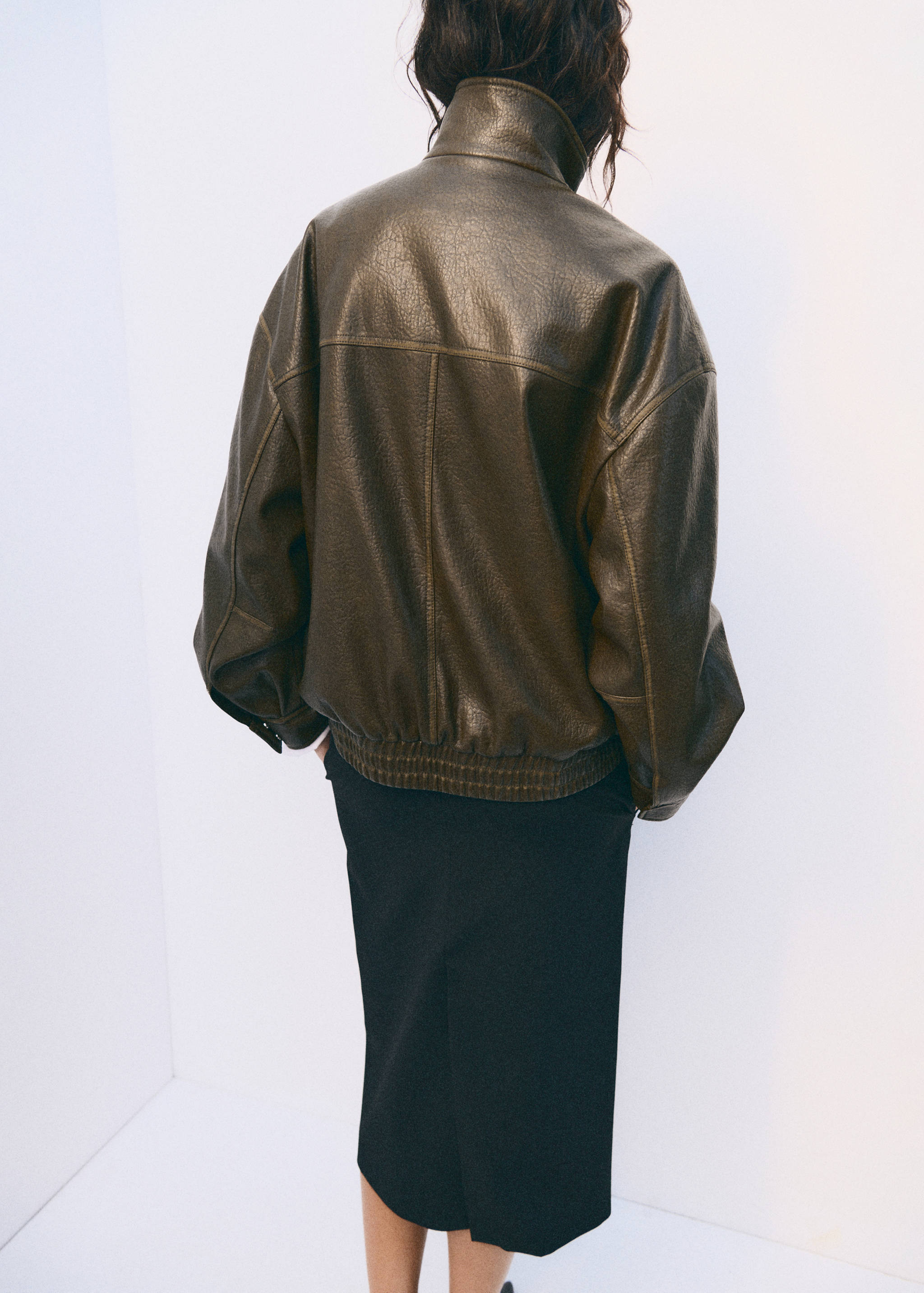 Back view of an oversized dark olive-green leather-look jacket with a high collar.
