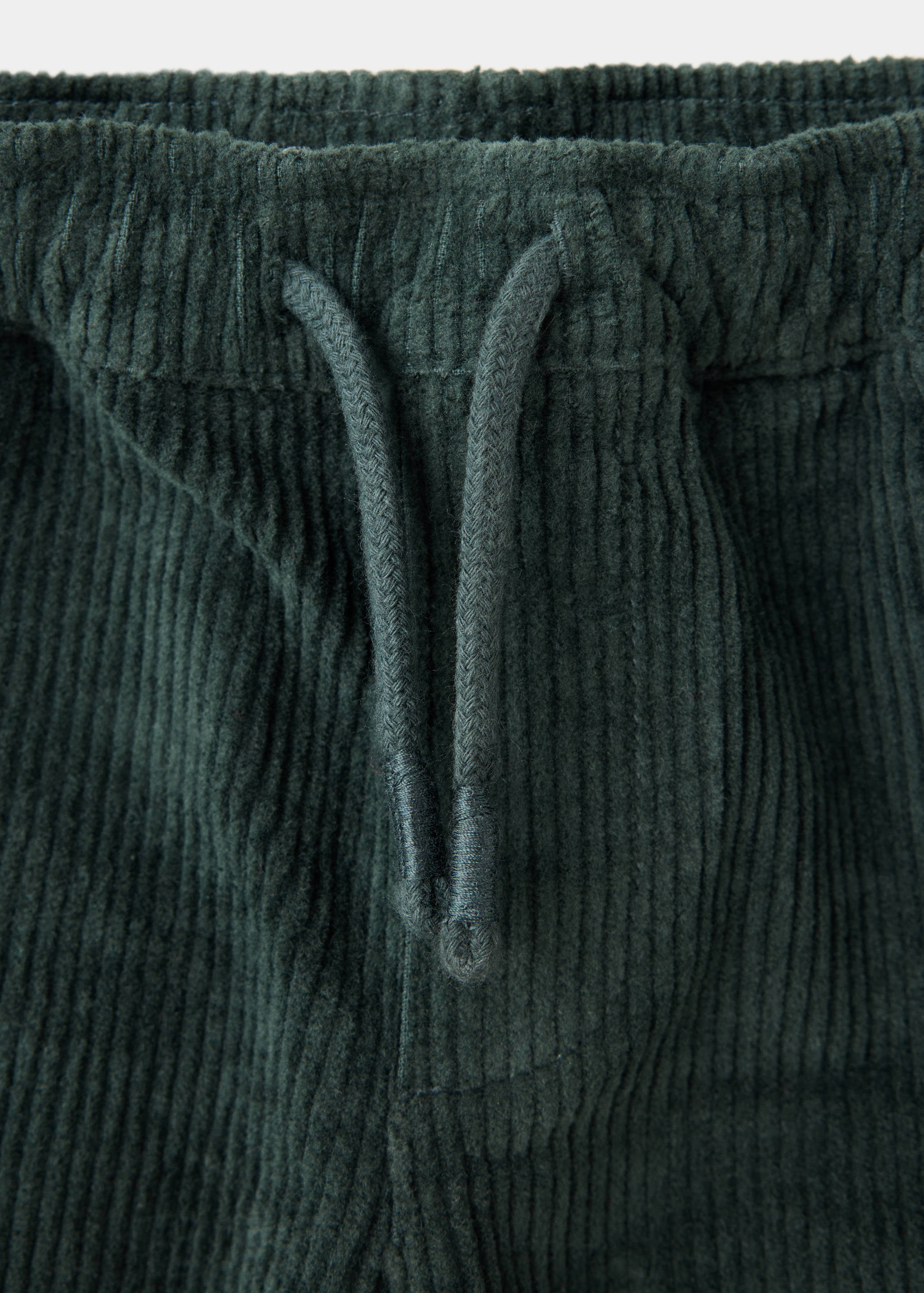 Dark green corduroy trousers detail showing the elasticated drawstring waistband.