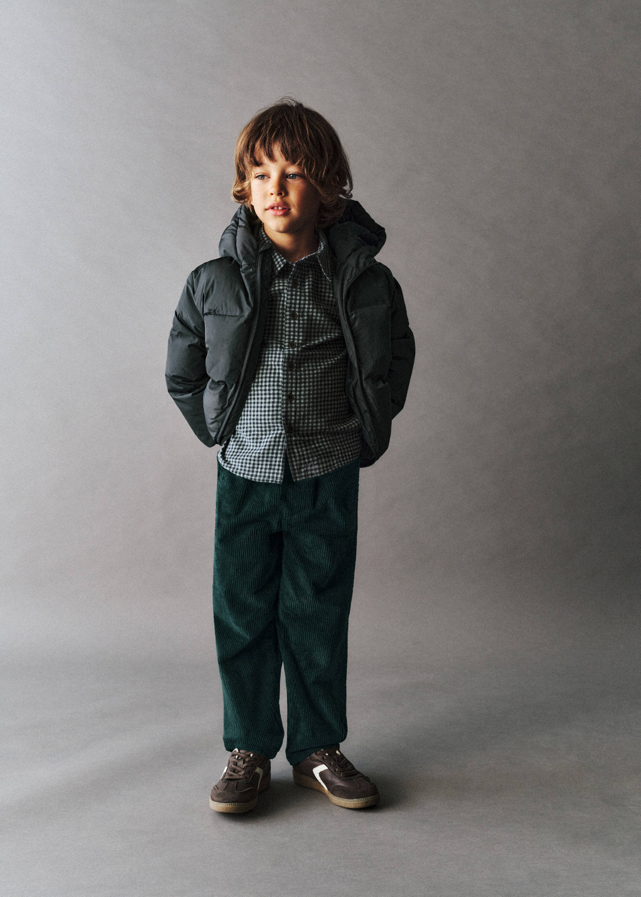 Dark green corduroy trousers with a relaxed fit, worn with a puffer jacket and checked shirt.