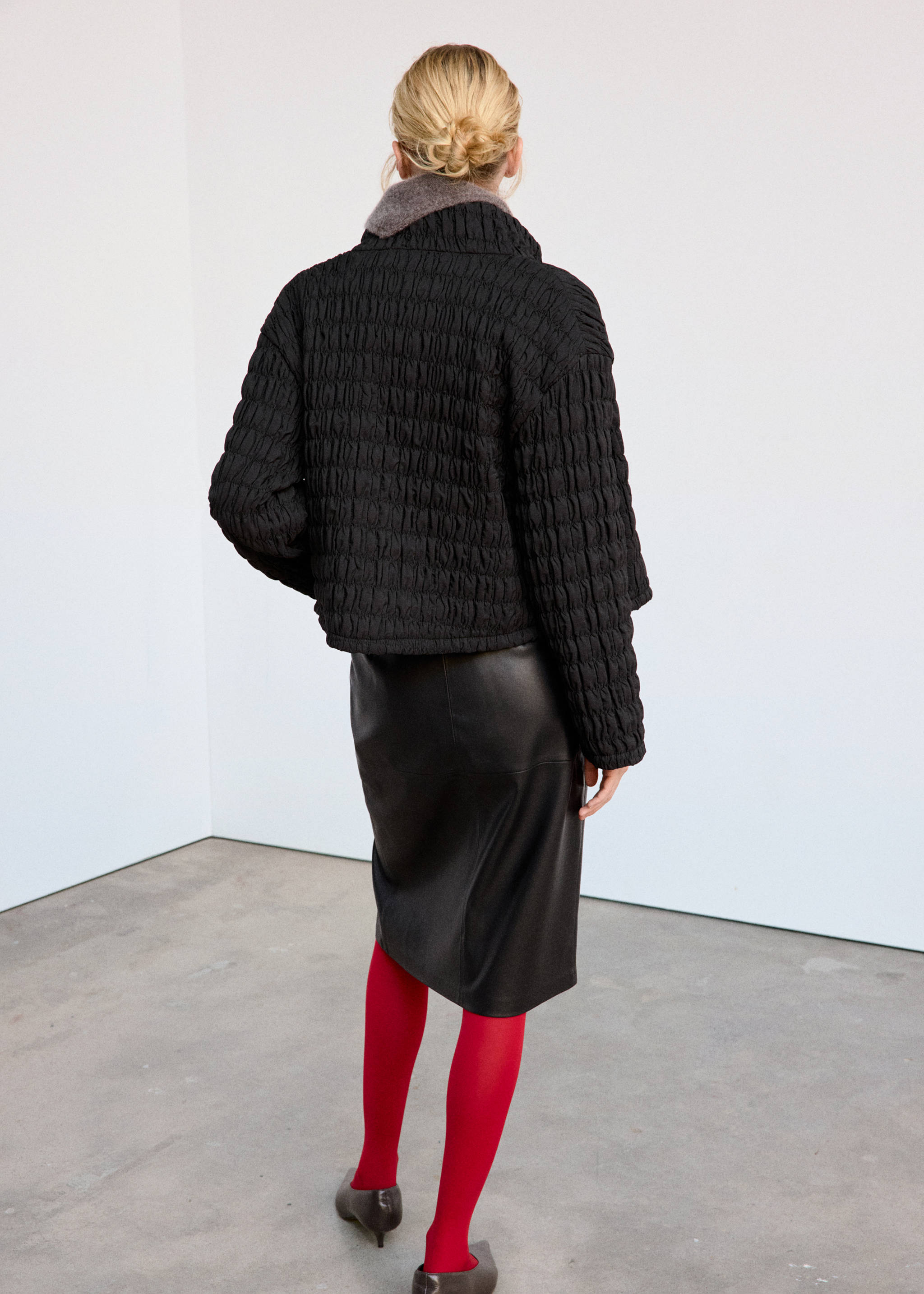 Black textured anorak from the back, featuring a high collar.