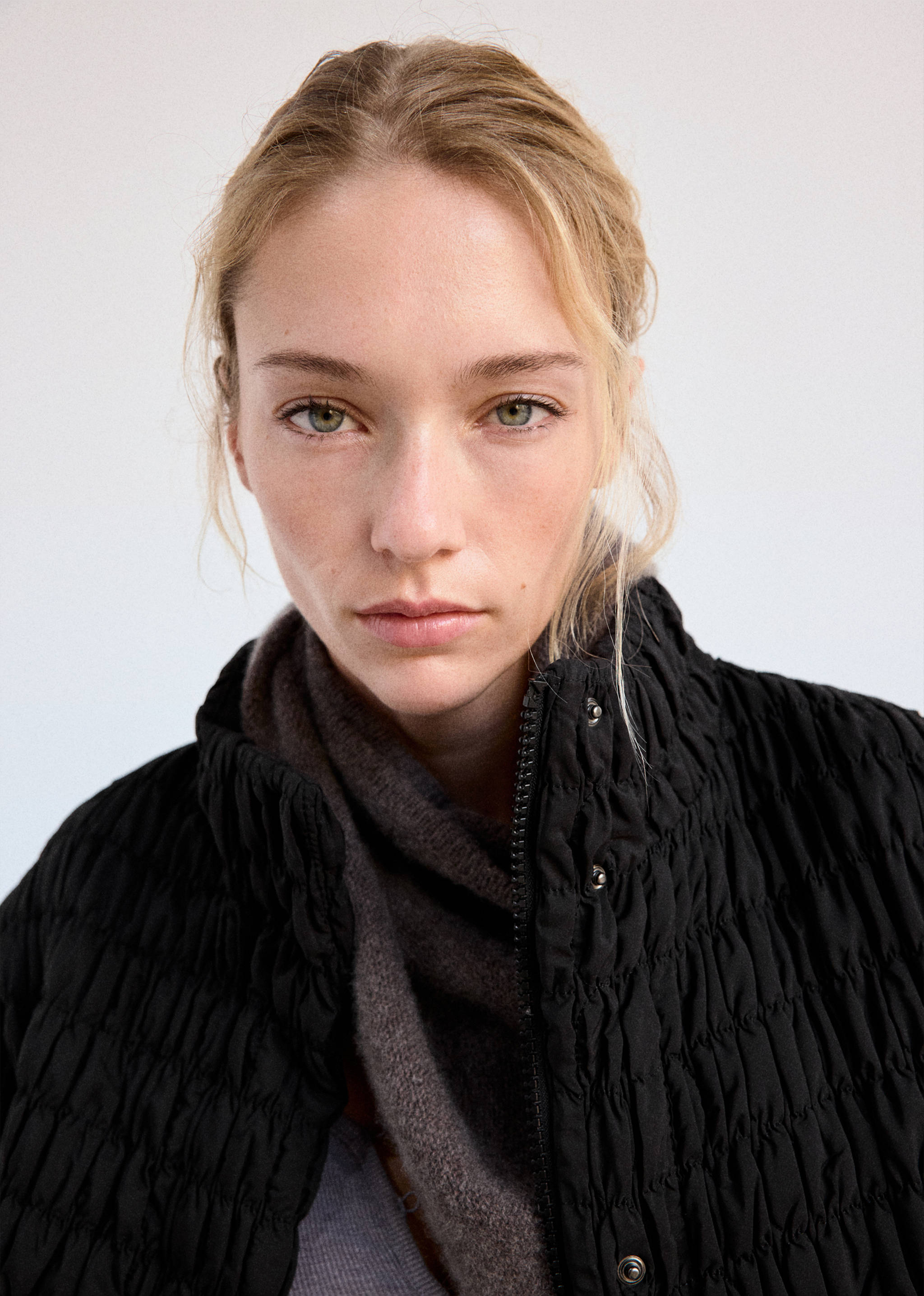 Close-up of a black anorak featuring a high ruffled shirred collar.