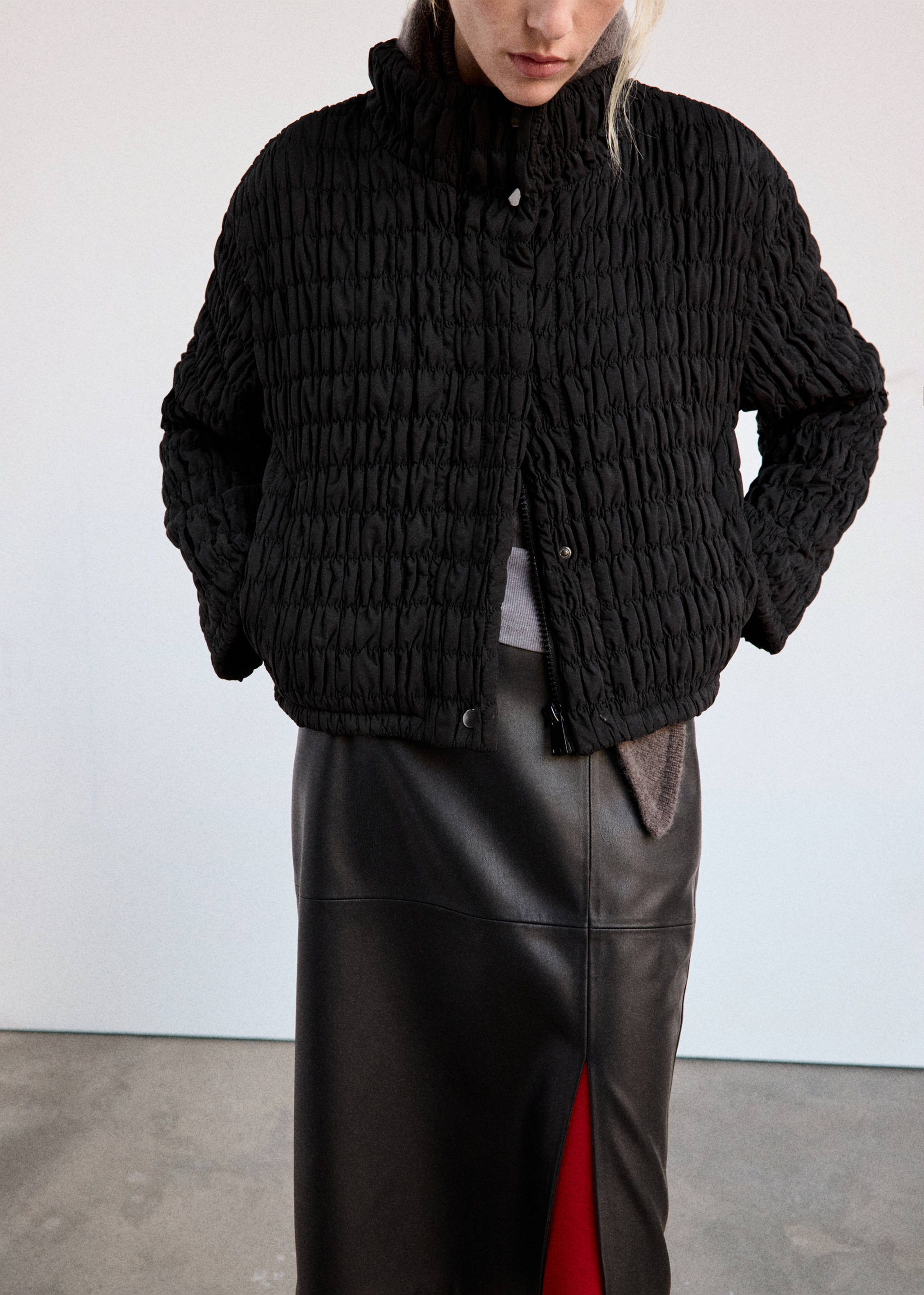Black quilted anorak with a high neck and puckered texture.