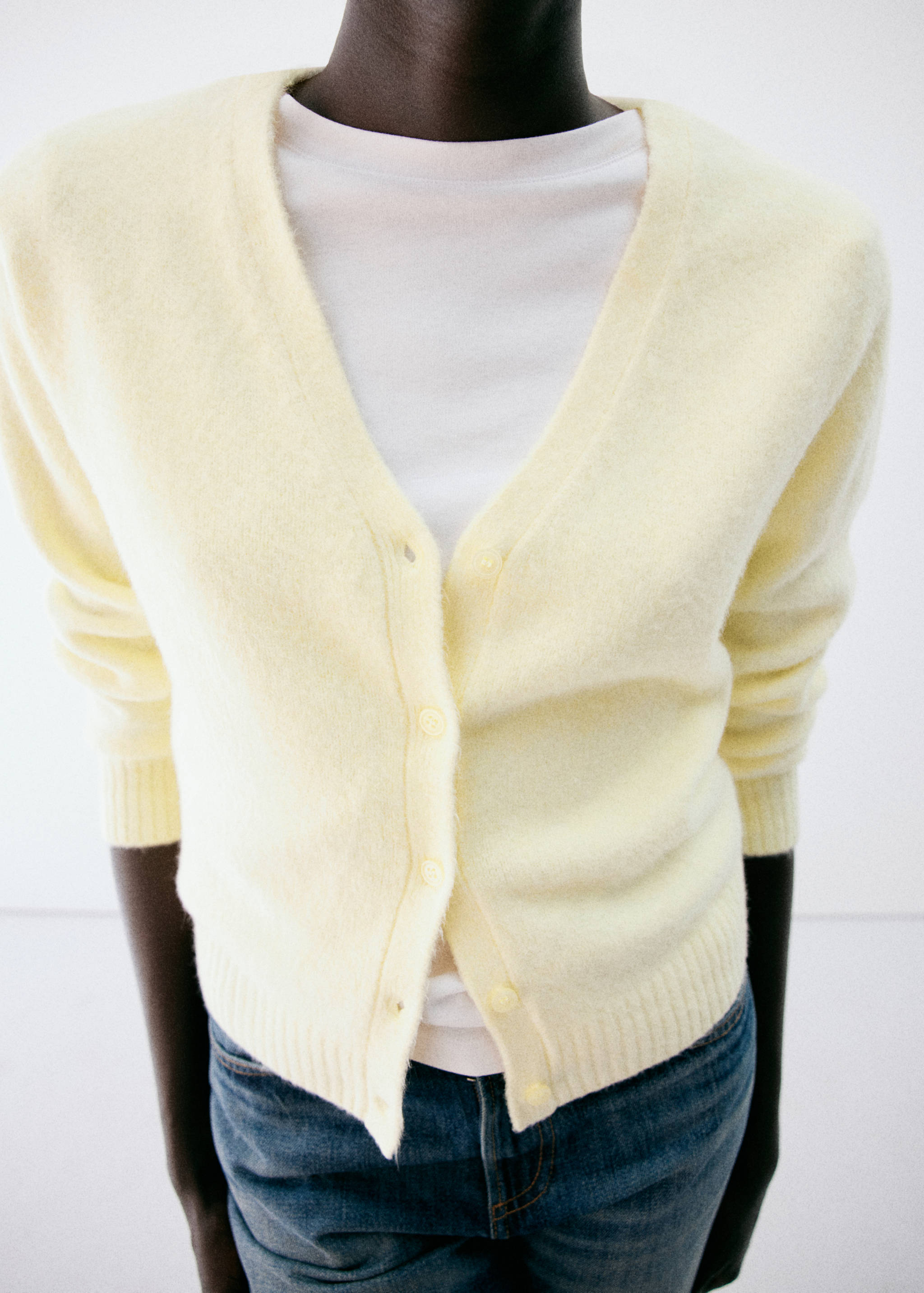 Pale yellow fuzzy V-neck cardigan worn over a white t-shirt.