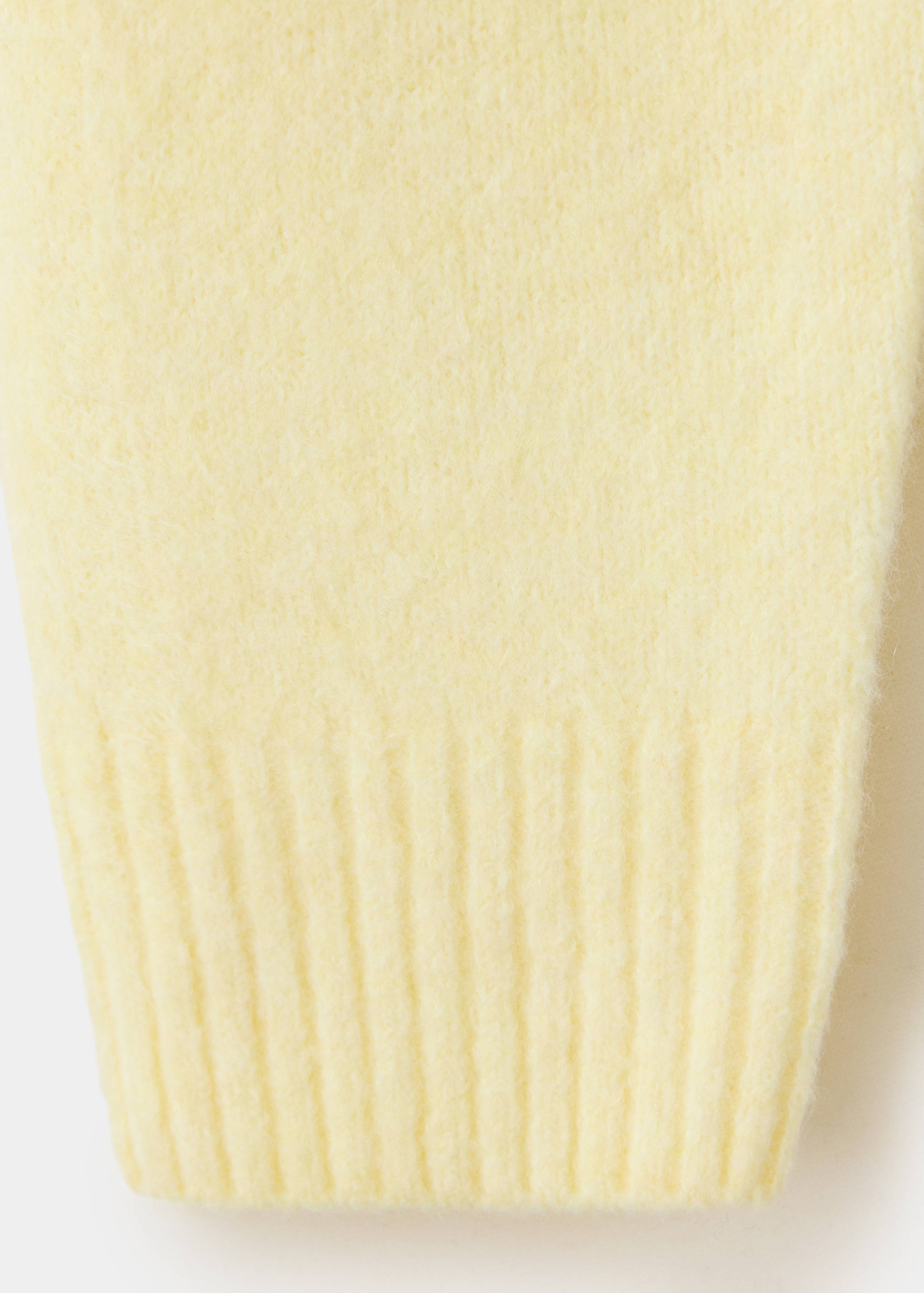 Close-up of a pale yellow cardigan's soft, fuzzy fabric and ribbed cuff.