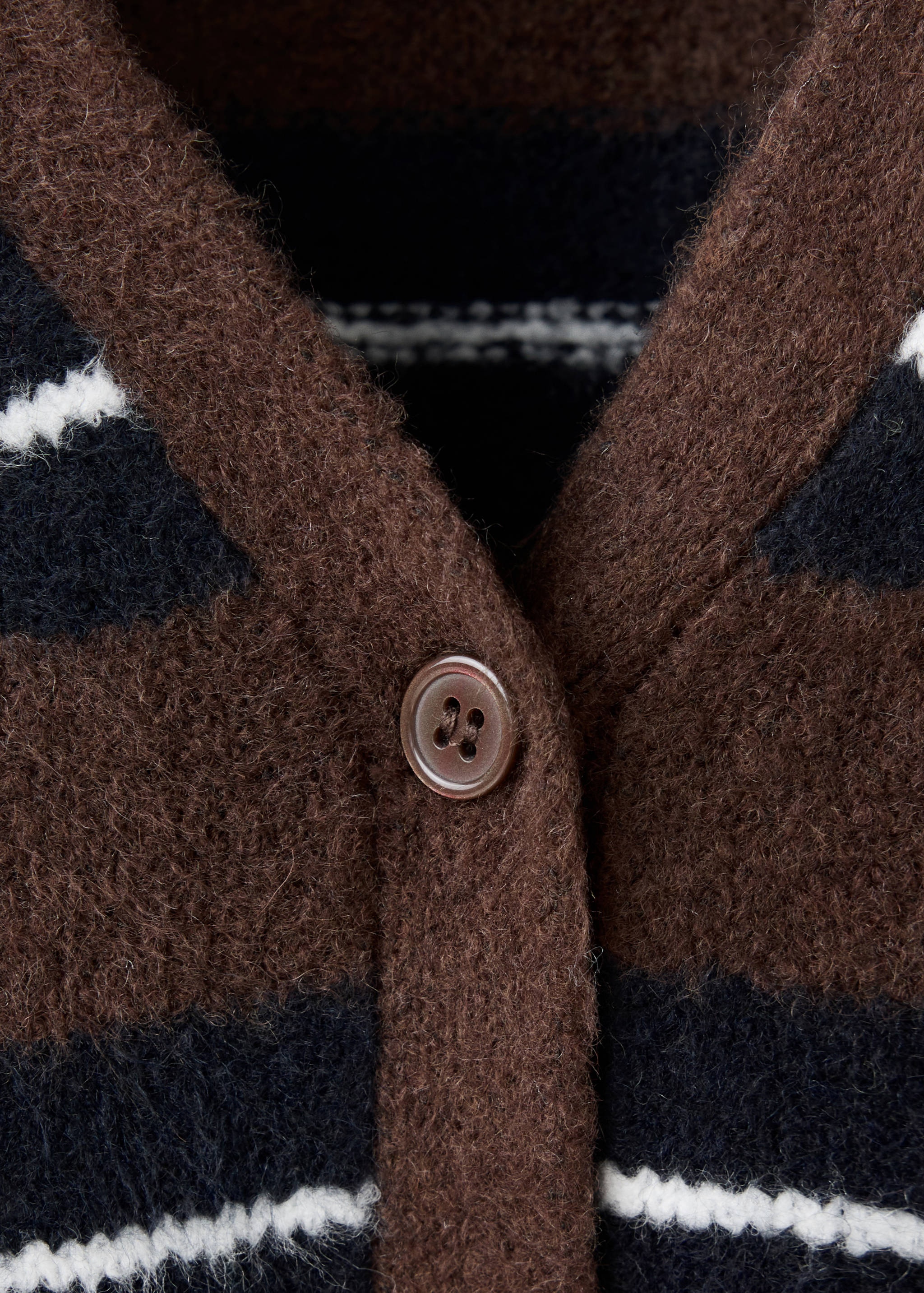Close-up of a striped knit cardigan featuring a V-neck and button closure.