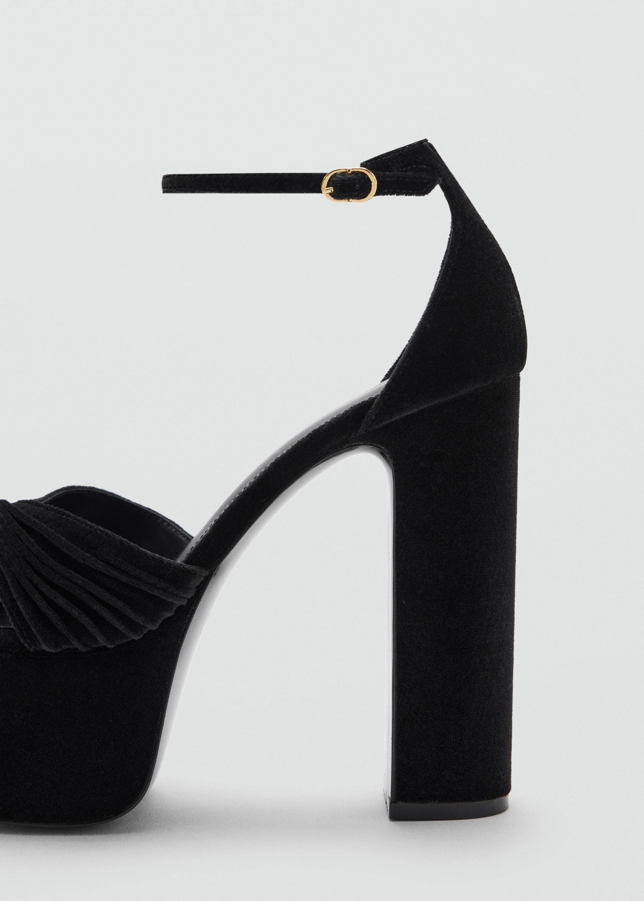 Close-up of a black heeled sandal with a platform and ankle strap.