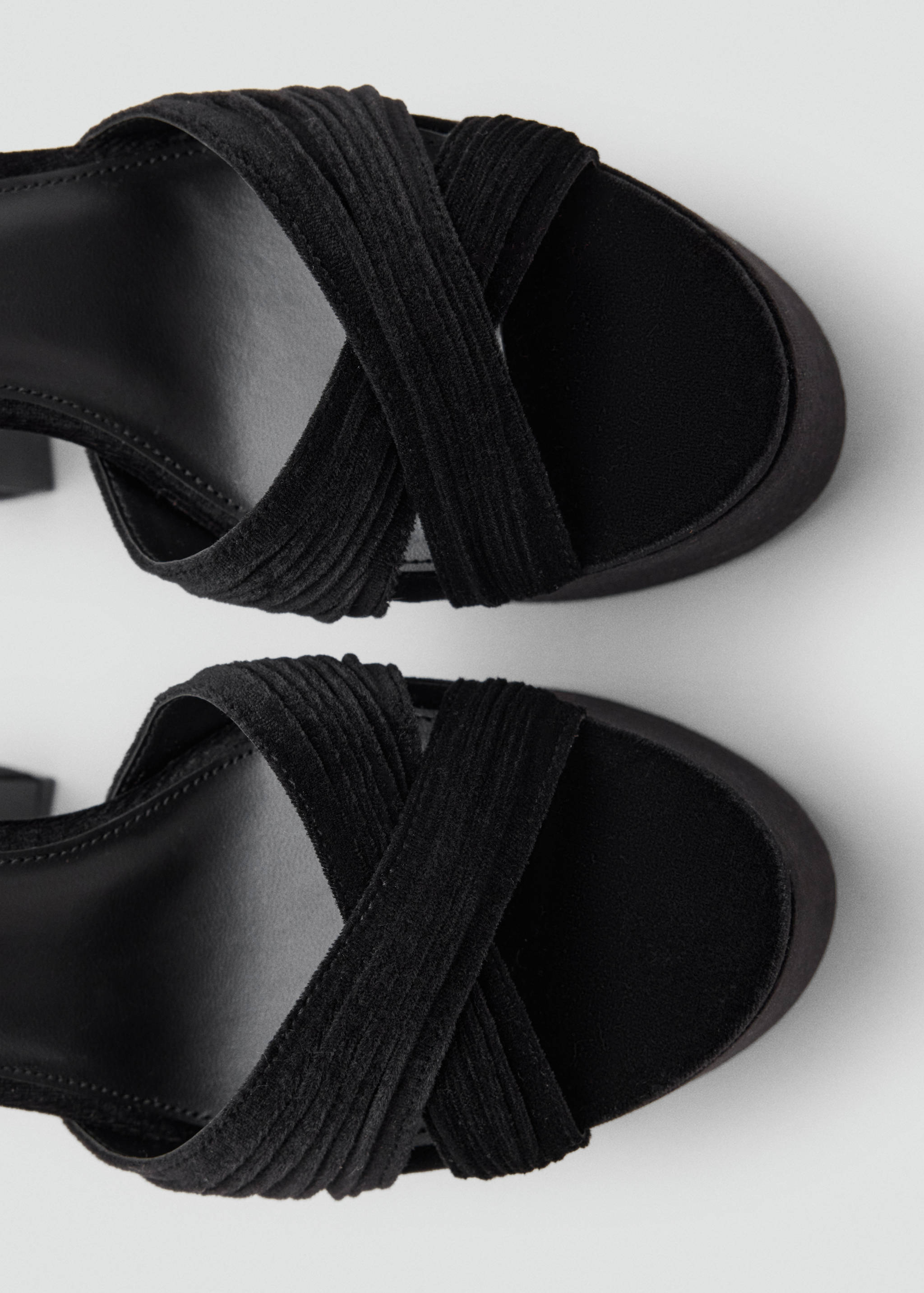 Close-up of black platform sandals with textured crisscross straps.