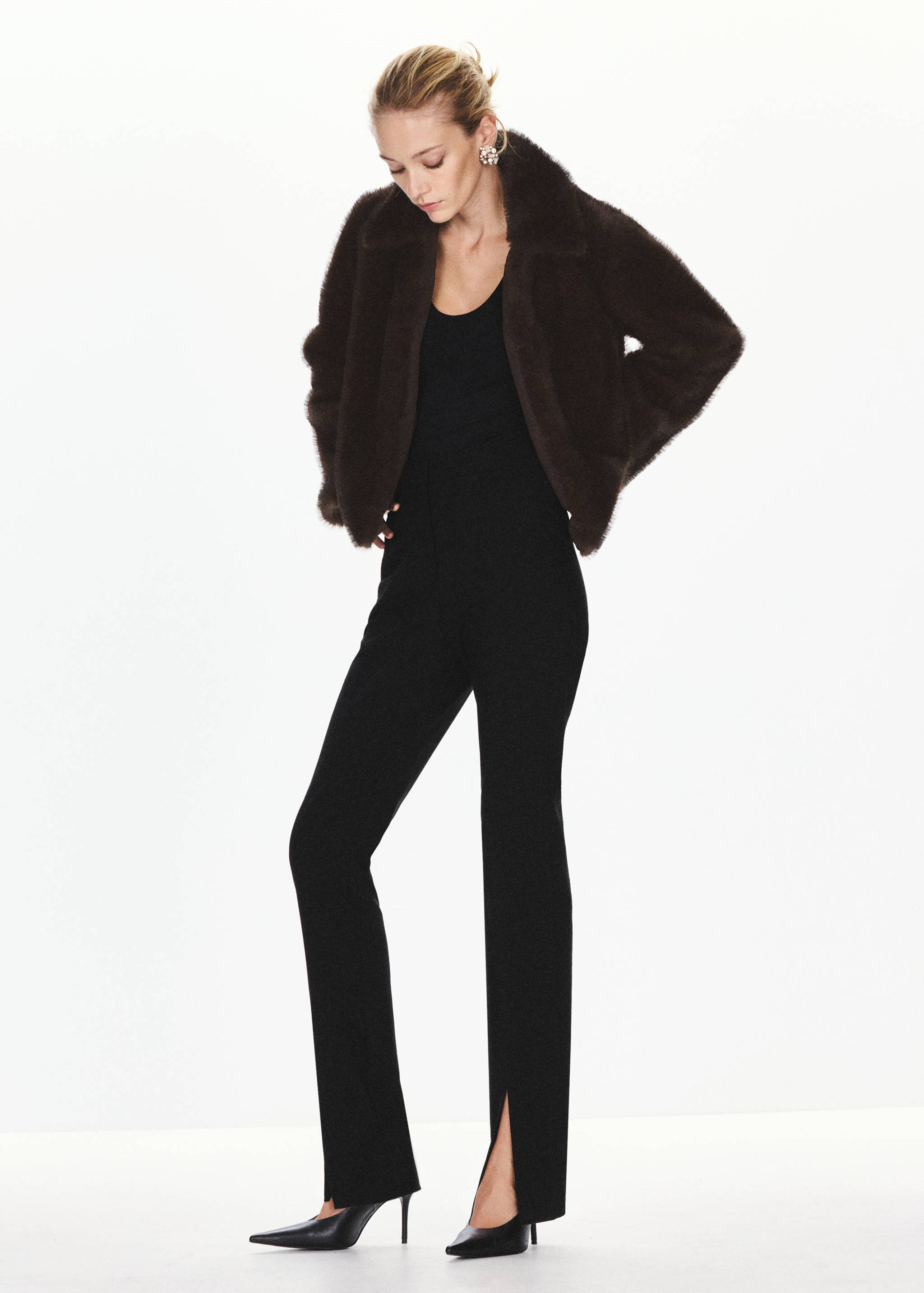 Dark brown faux-fur jacket worn over a black top and matching trousers with hem slits.