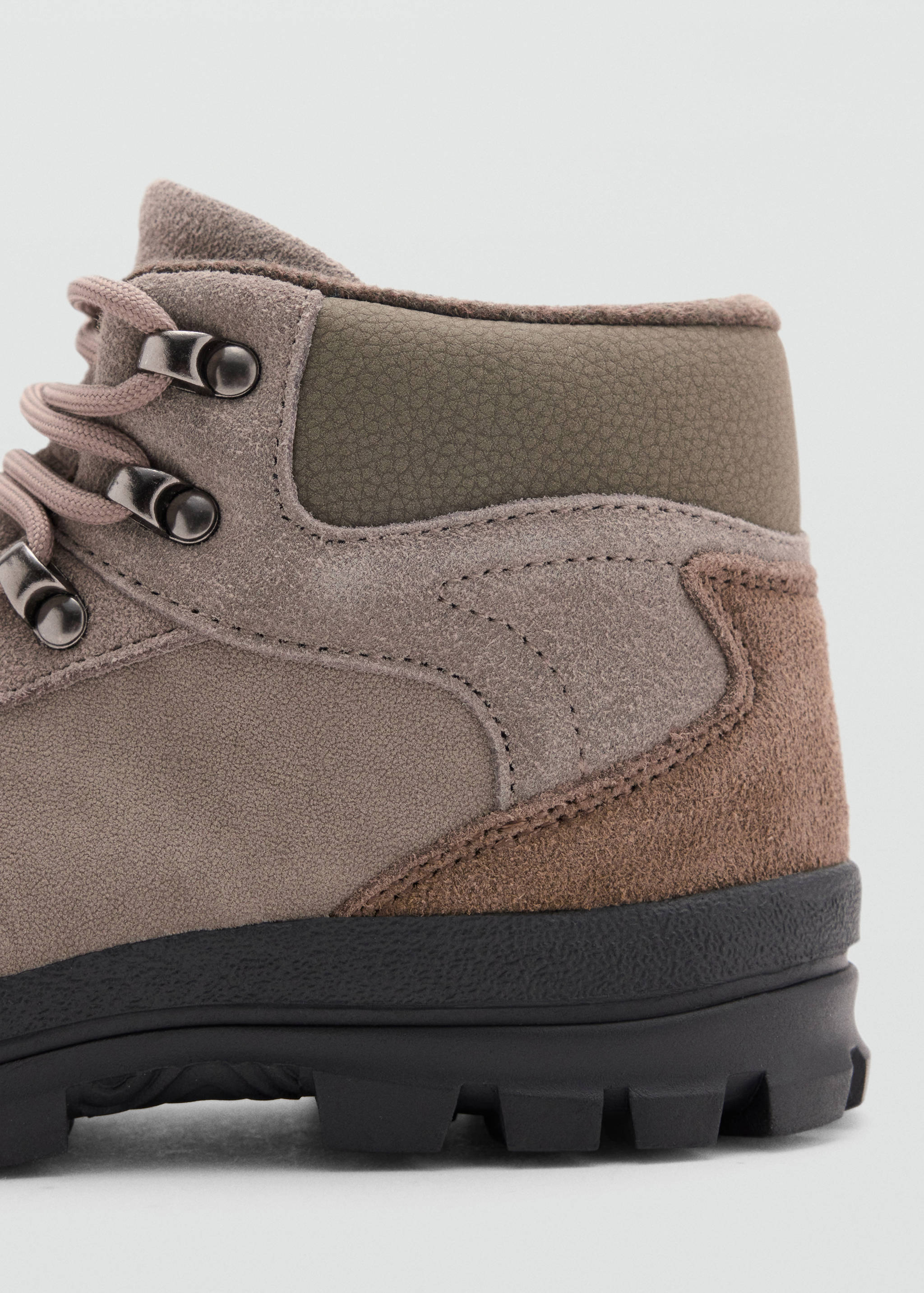 Close-up of a taupe children's ankle boot with an olive-green padded collar and black treaded sole.