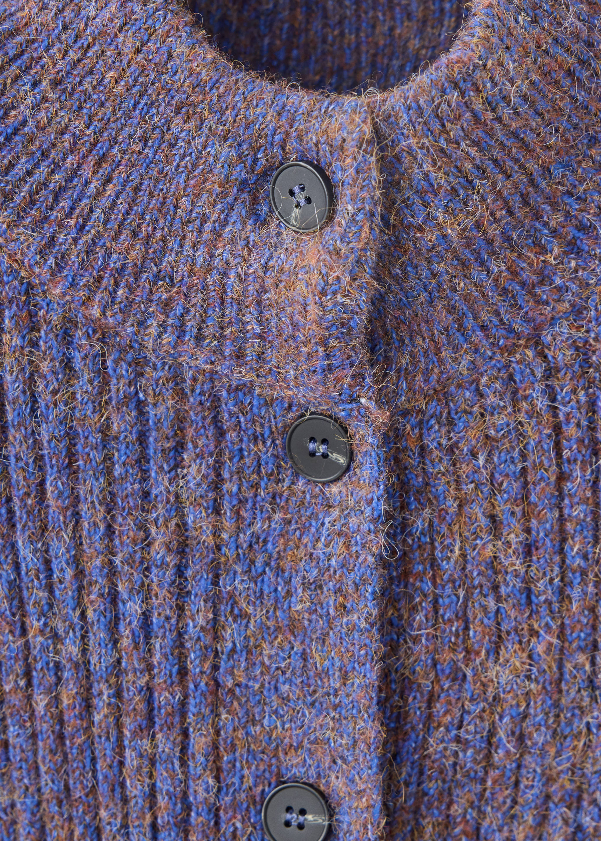 Close-up of a blue and brown marled knit cardigan with buttons.
