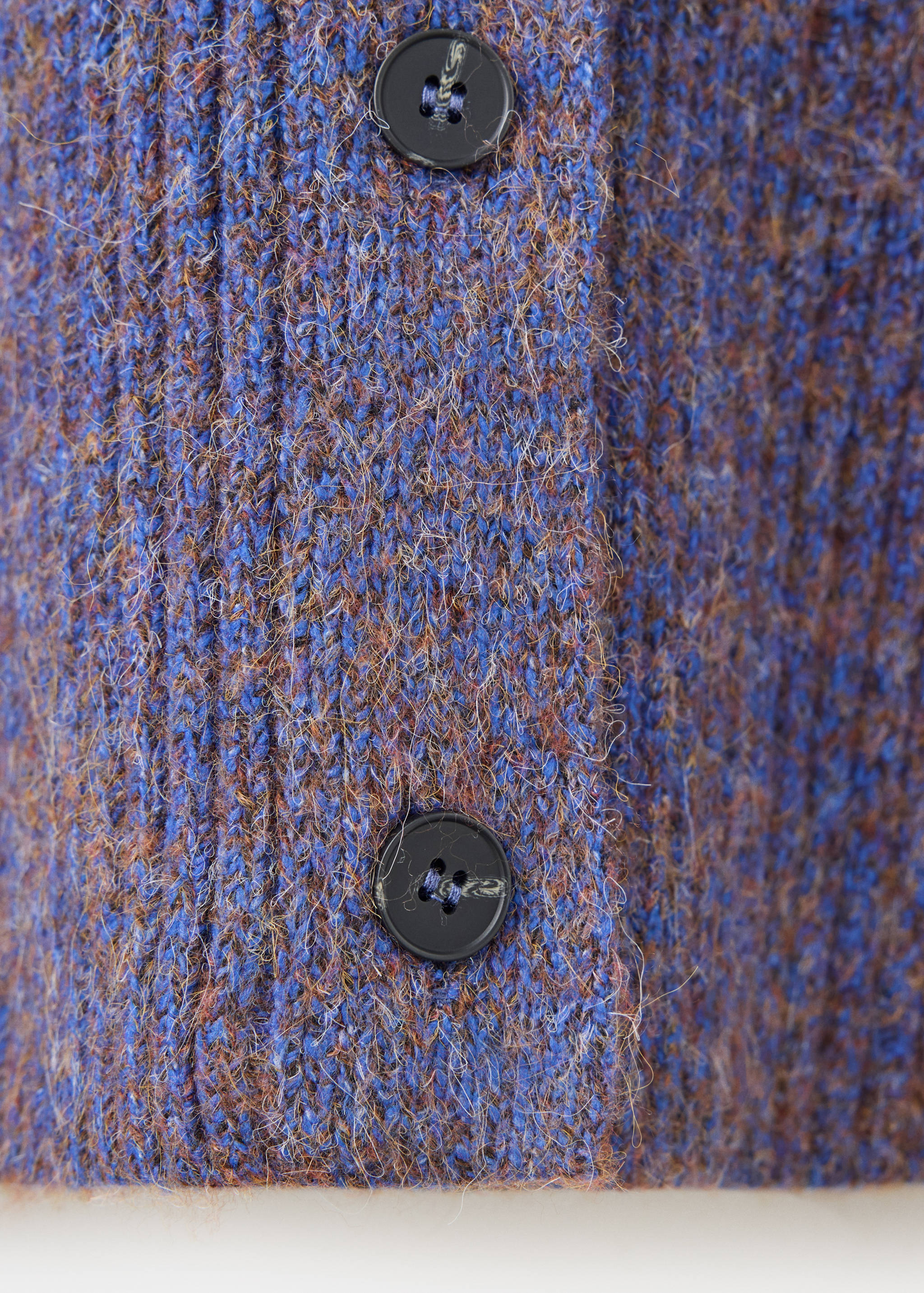 Blue textured knit cardigan fabric close-up with buttons.