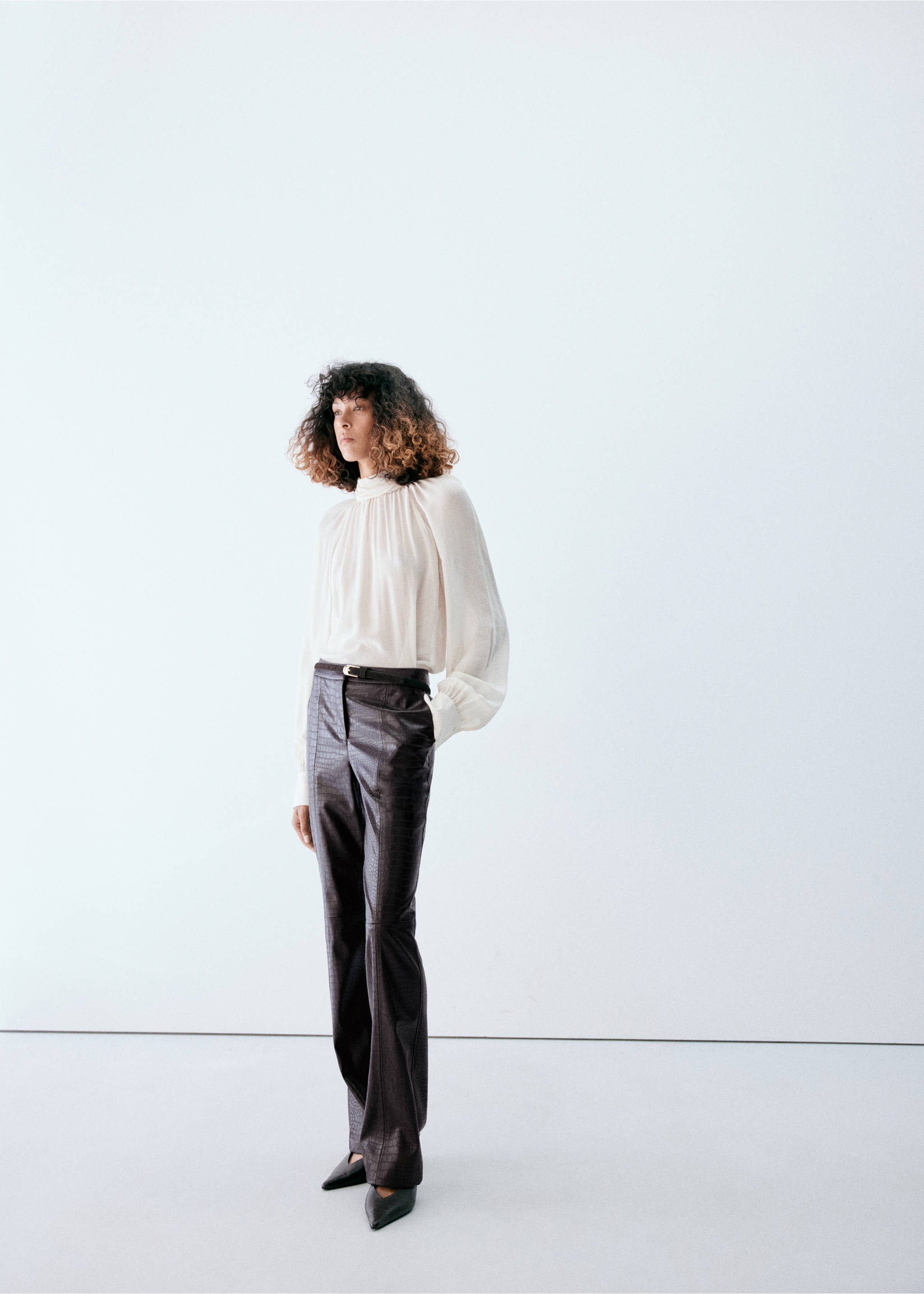 Dark brown crocodile-effect trousers styled with a cream-coloured high-neck blouse., Chocolate. Ref: 37047789-00.
