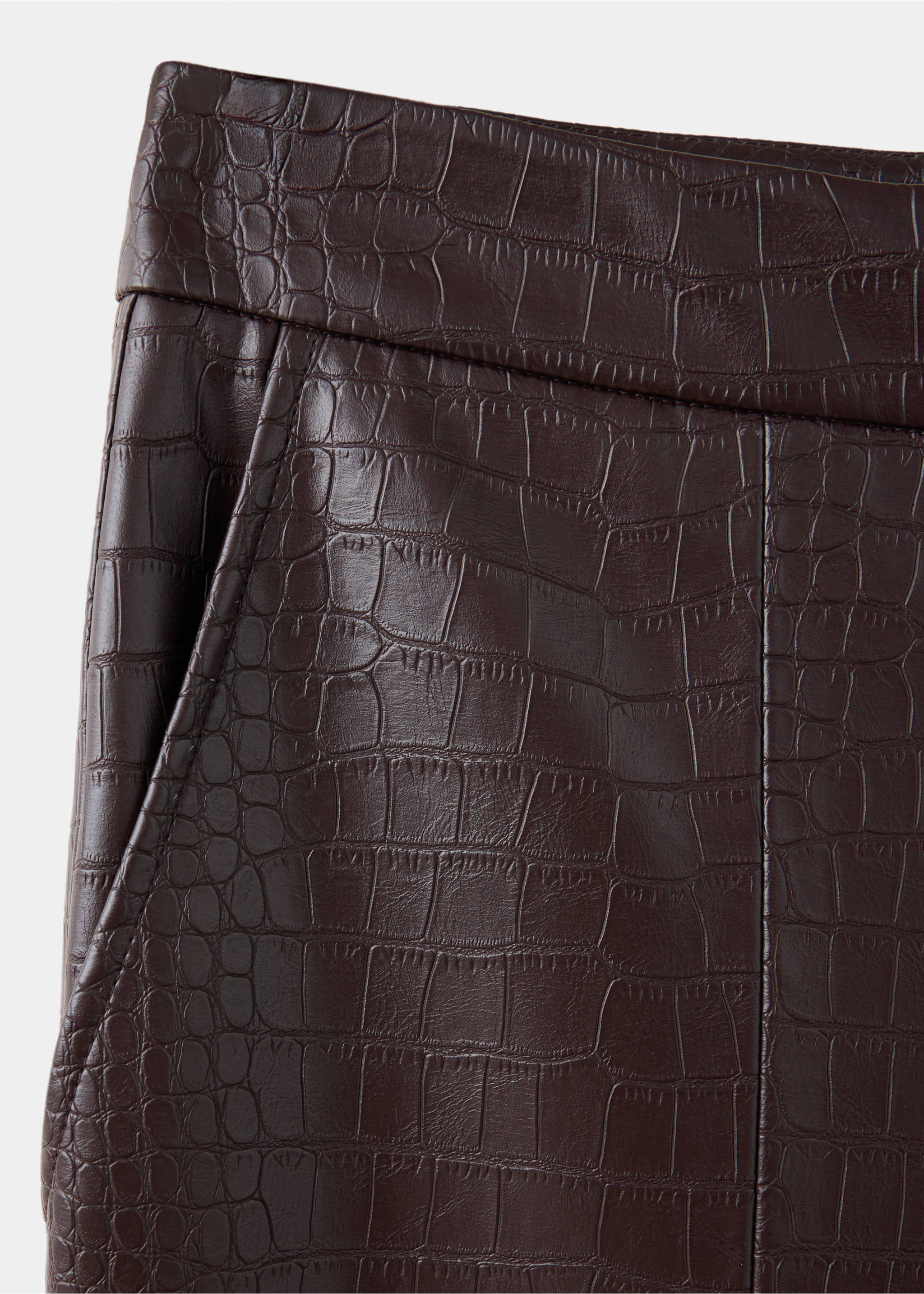 Close-up of dark brown crocodile-embossed trousers fabric texture., Chocolate. Ref: 37047789-00.