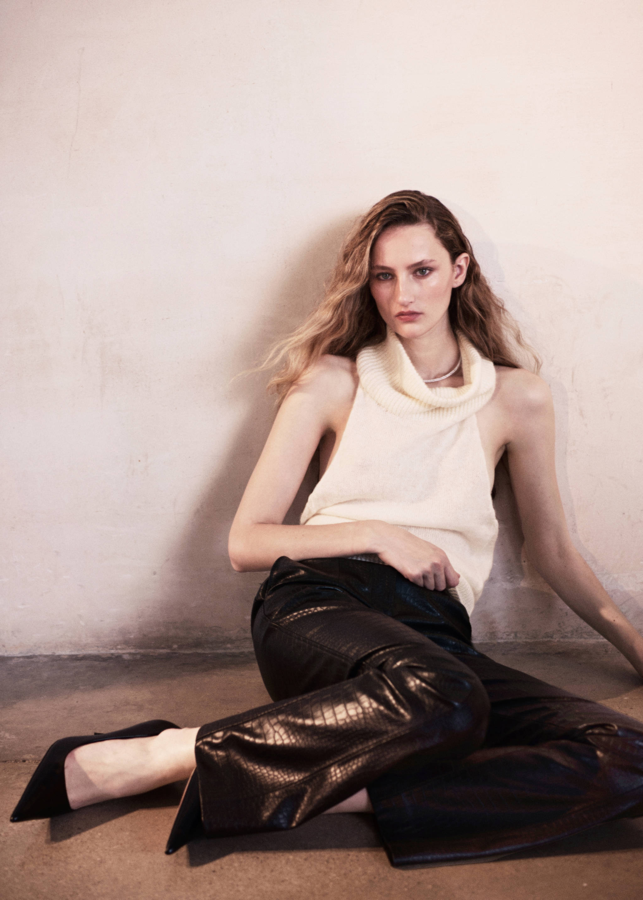 Dark brown textured trousers worn with a sleeveless cream knit top.