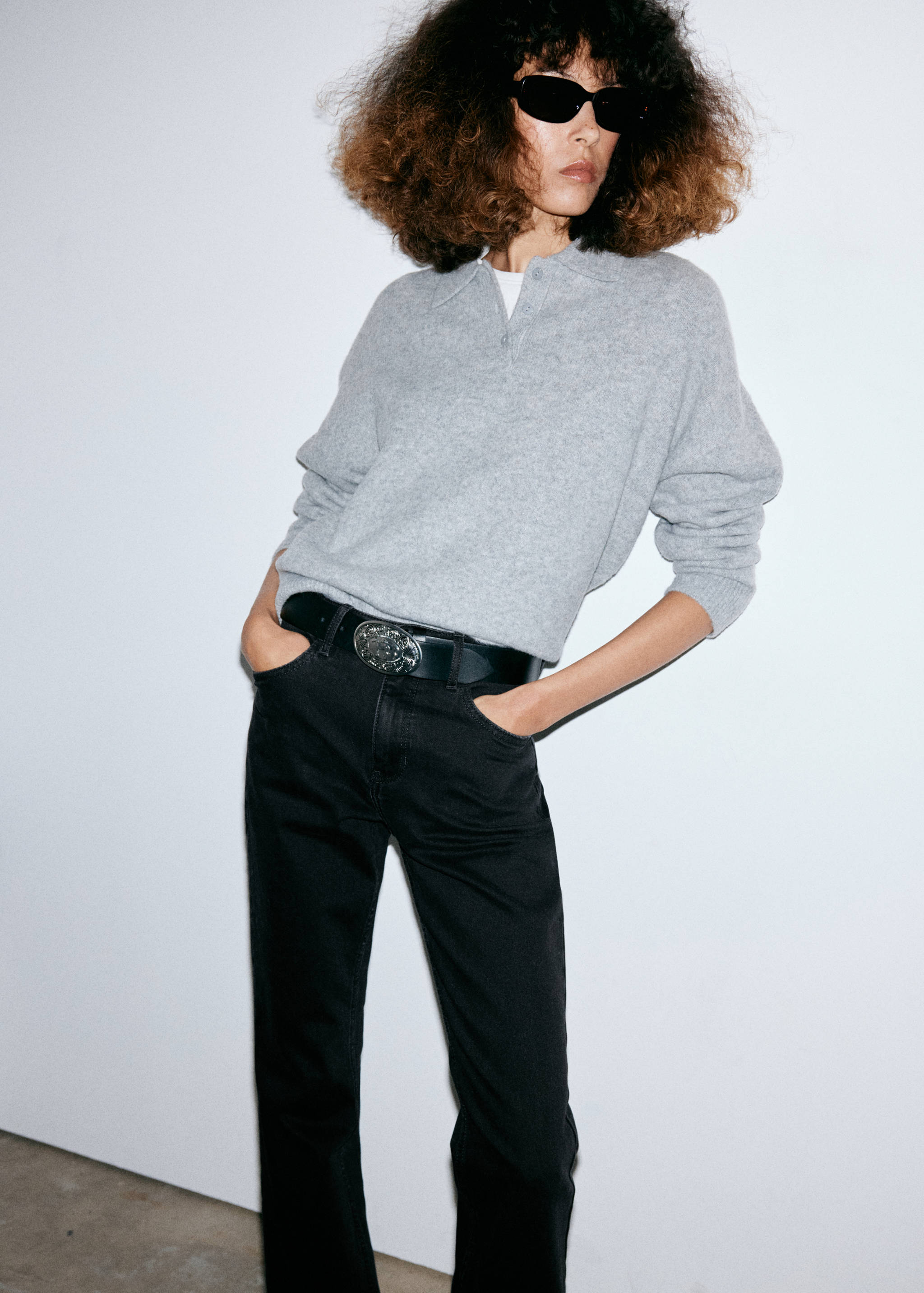 Black jeans worn with a grey polo sweater and a statement belt.